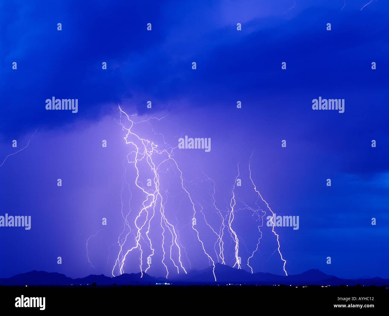 Lightning bolts strike a mountain range from a brilliant blue sky ...