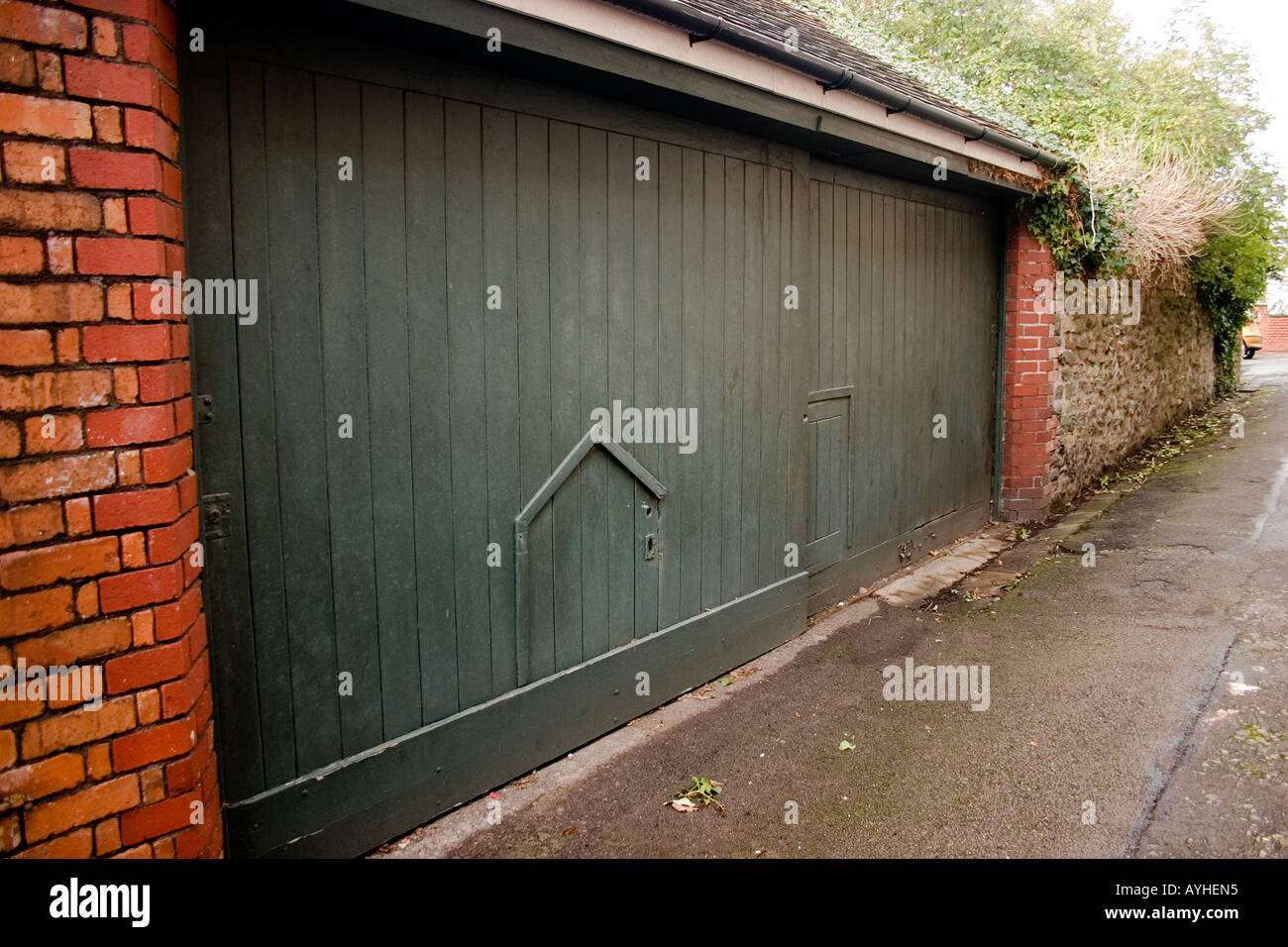 Two odd small doors set into a larger pair of garage doors Cardiff UK Stock Photo