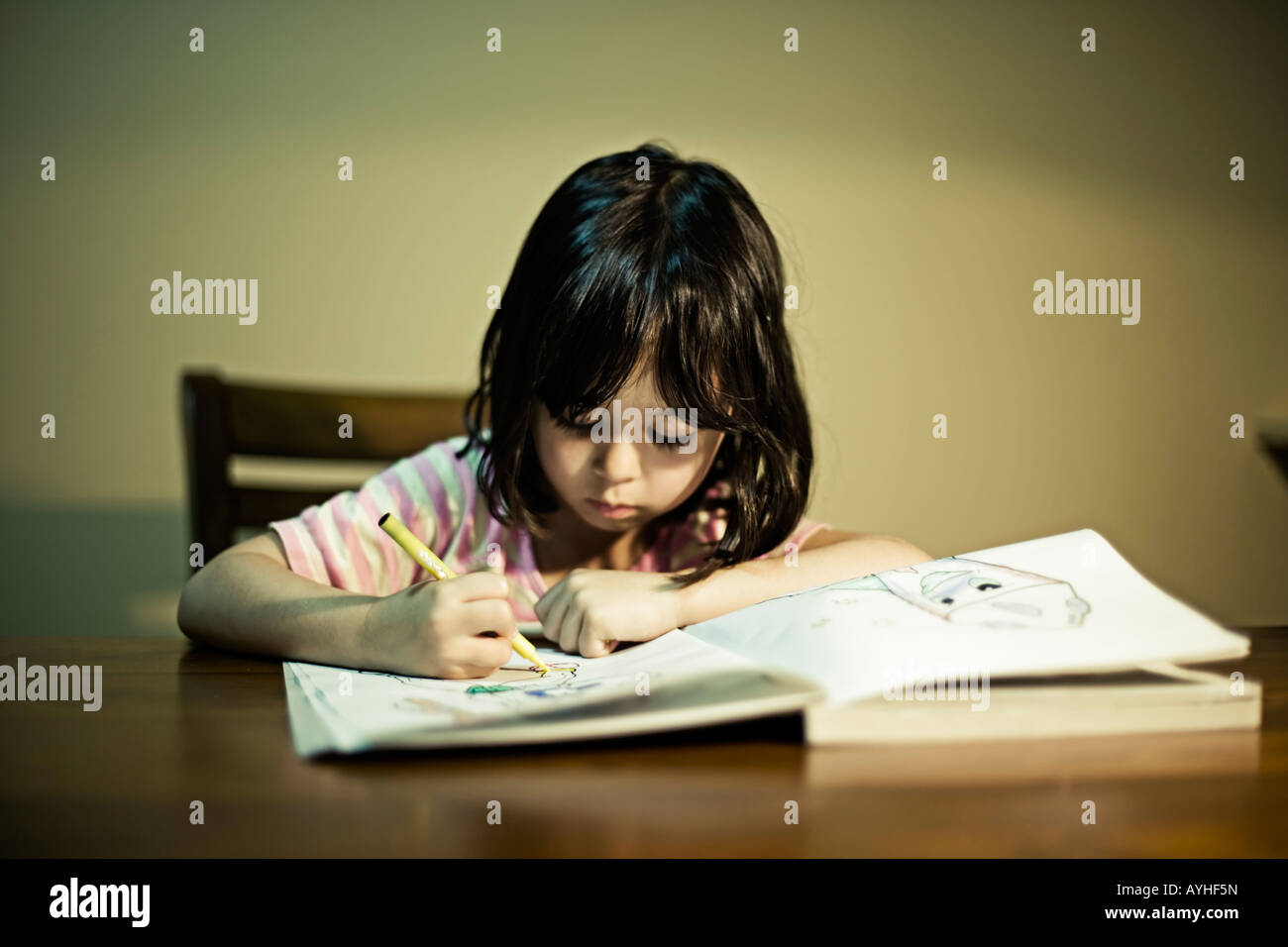 Girl four years old concentrates on her colouring book Stock Photo