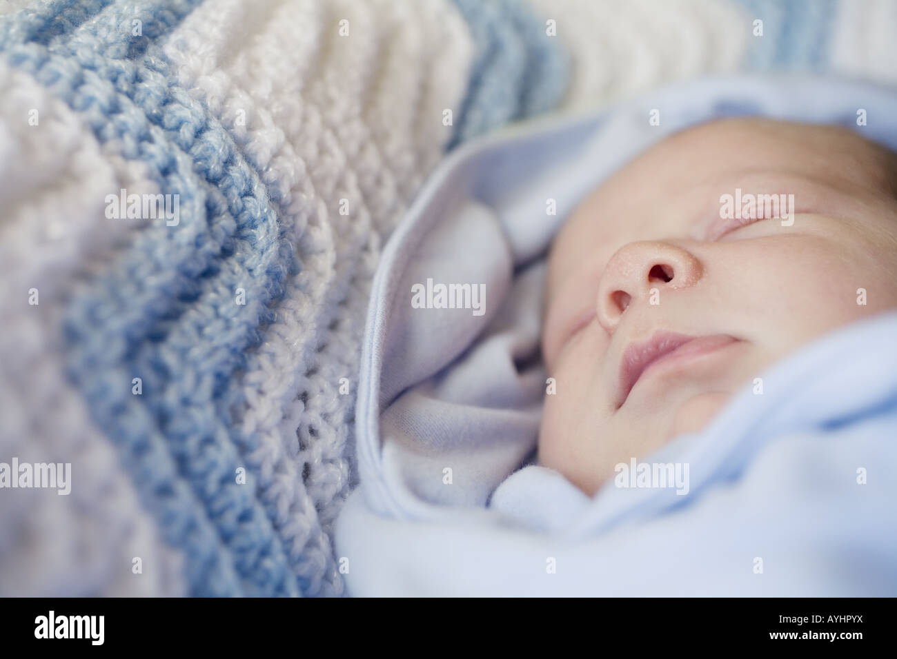 A sleeping baby swaddled in a blue blanket Stock Photo Alamy