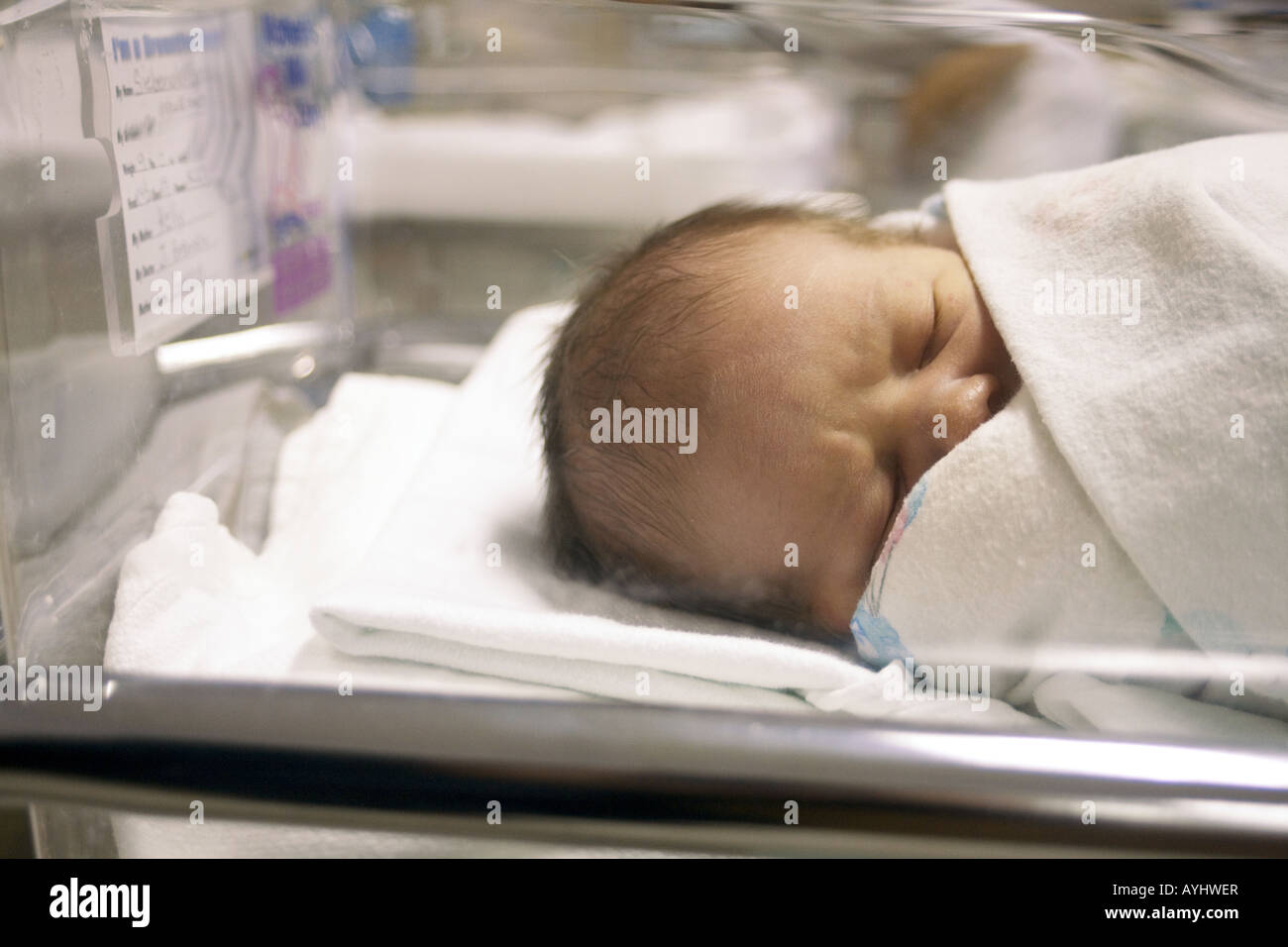 A newborn baby sleeping in a hospital nursery bed after childbirth. Stock Photo