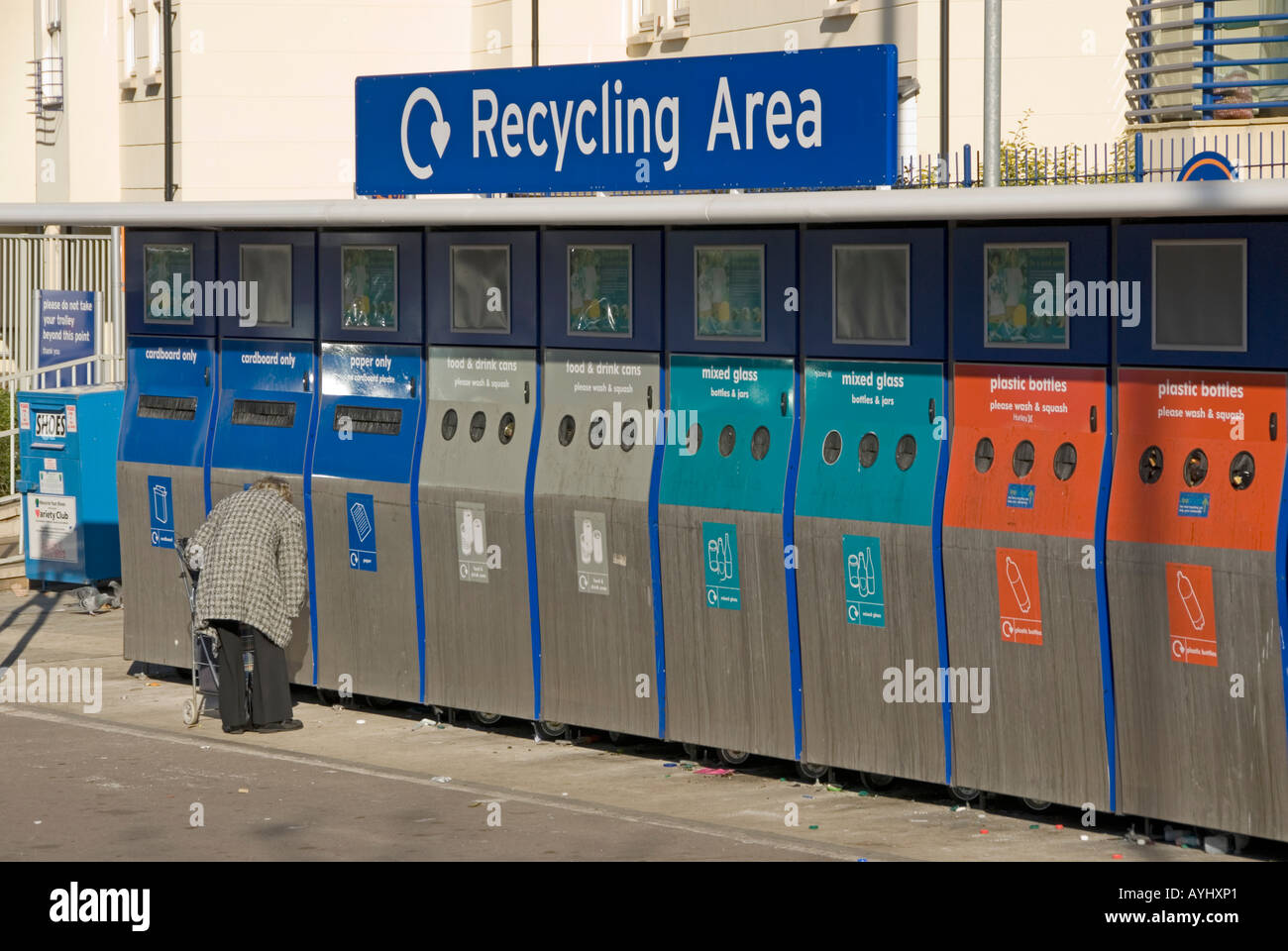 Lady with pushchair unloading household waste into recycling collection bins at Sainsburys supermarket Stock Photo