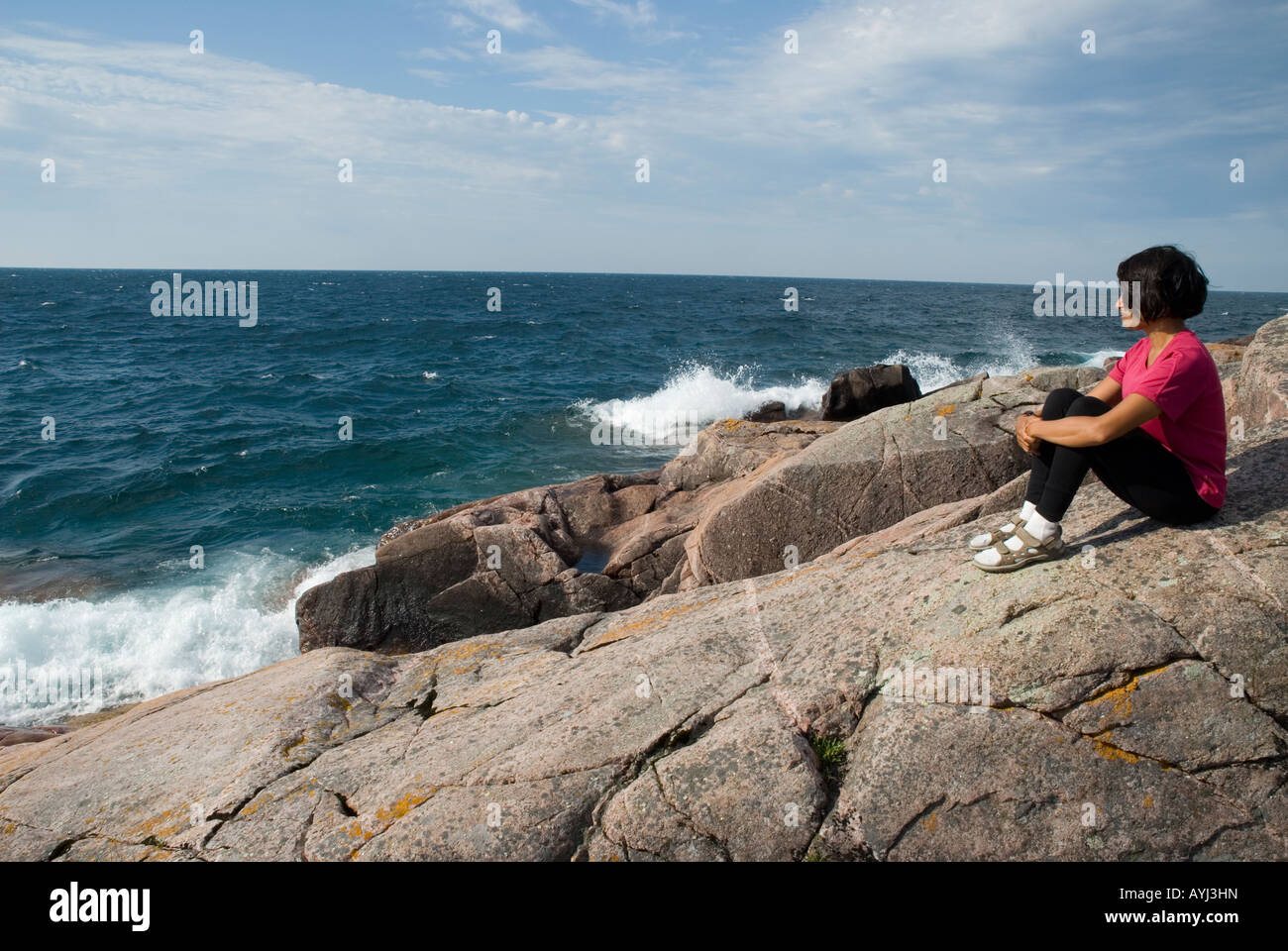 woman sitting on rocky coast of lake superior Stock Photo