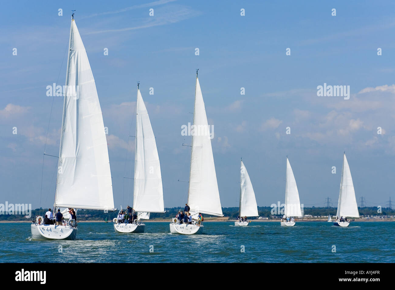 Six fully crewed yachts out sailing all with white sails Stock Photo