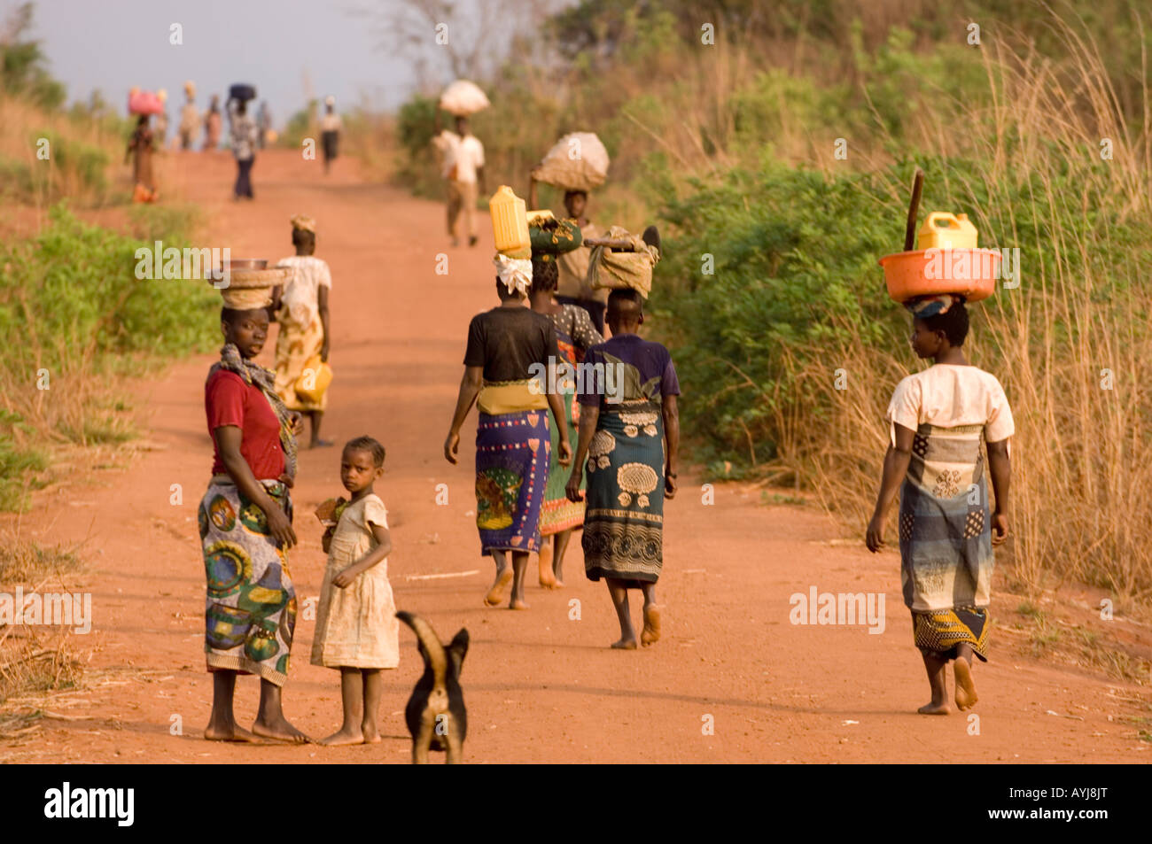 Villagers walking along a red dusty road to the next village in the