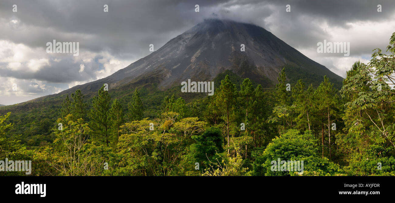 Panorama of active smoking Arenal volcano with storm clouds and  burning cinder blocks tumbling down slope Costa Rica Stock Photo