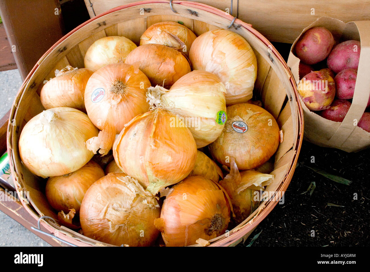 Wicker basket of yellow onions and bag of red potatoes at outdoor vegetable strand. Sauk Centre Minnesota USA Stock Photo