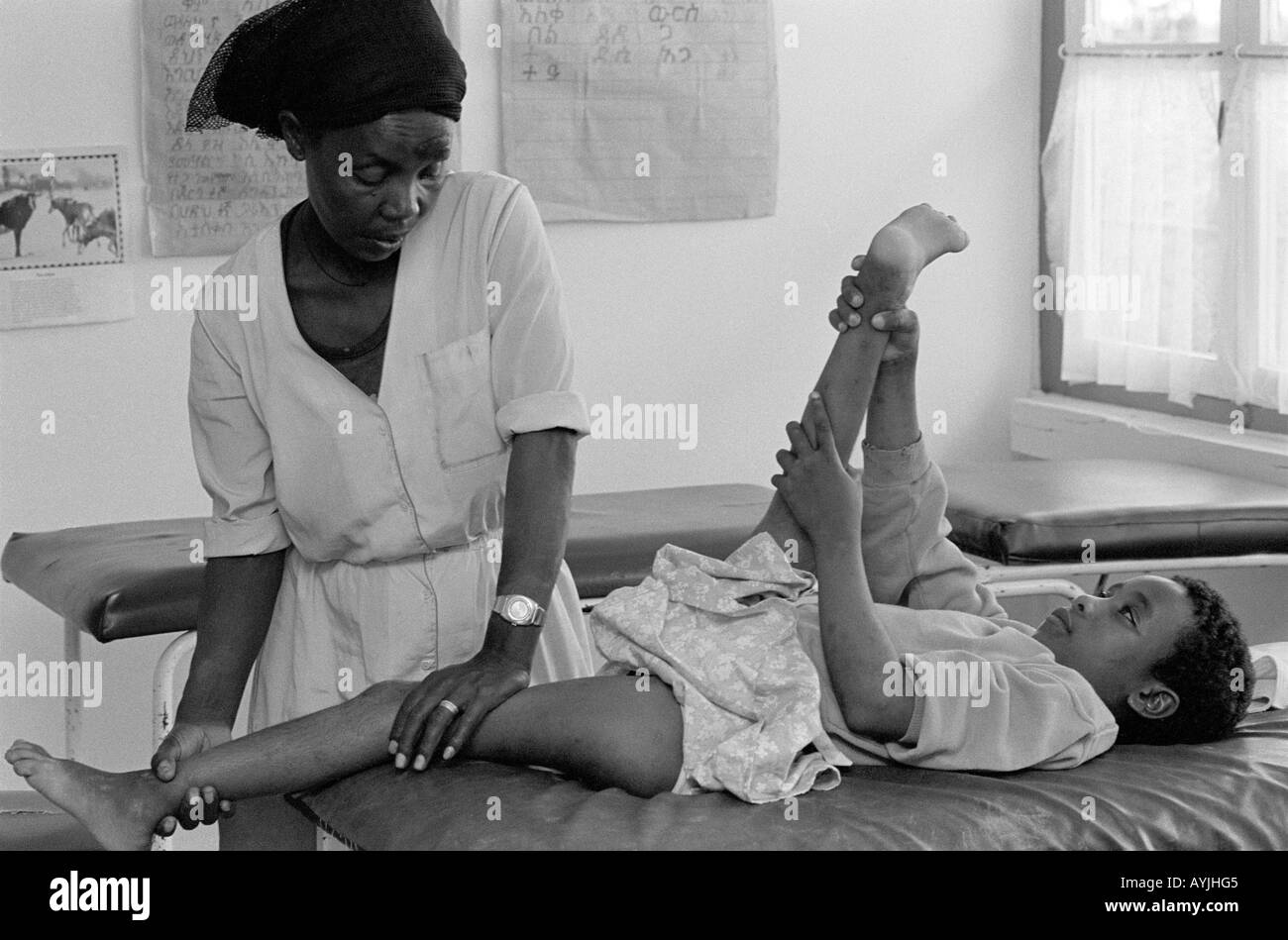 B/W of a female physiotherapist manipulating the legs of a young boy, a victim of polio, at a clinic in Asele, Shoa, Ethiopia, Africa Stock Photo