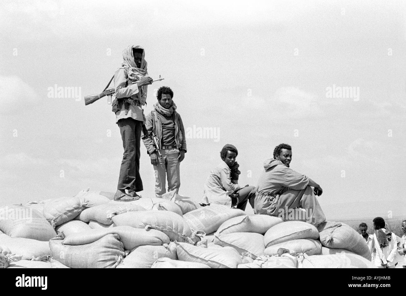 B/W of Ethiopian soldiers with kalashnikovs guarding sacks of food aid to be distributed to Somalis in Kebrebeyah Refugee Camp, Ethiopia. Stock Photo