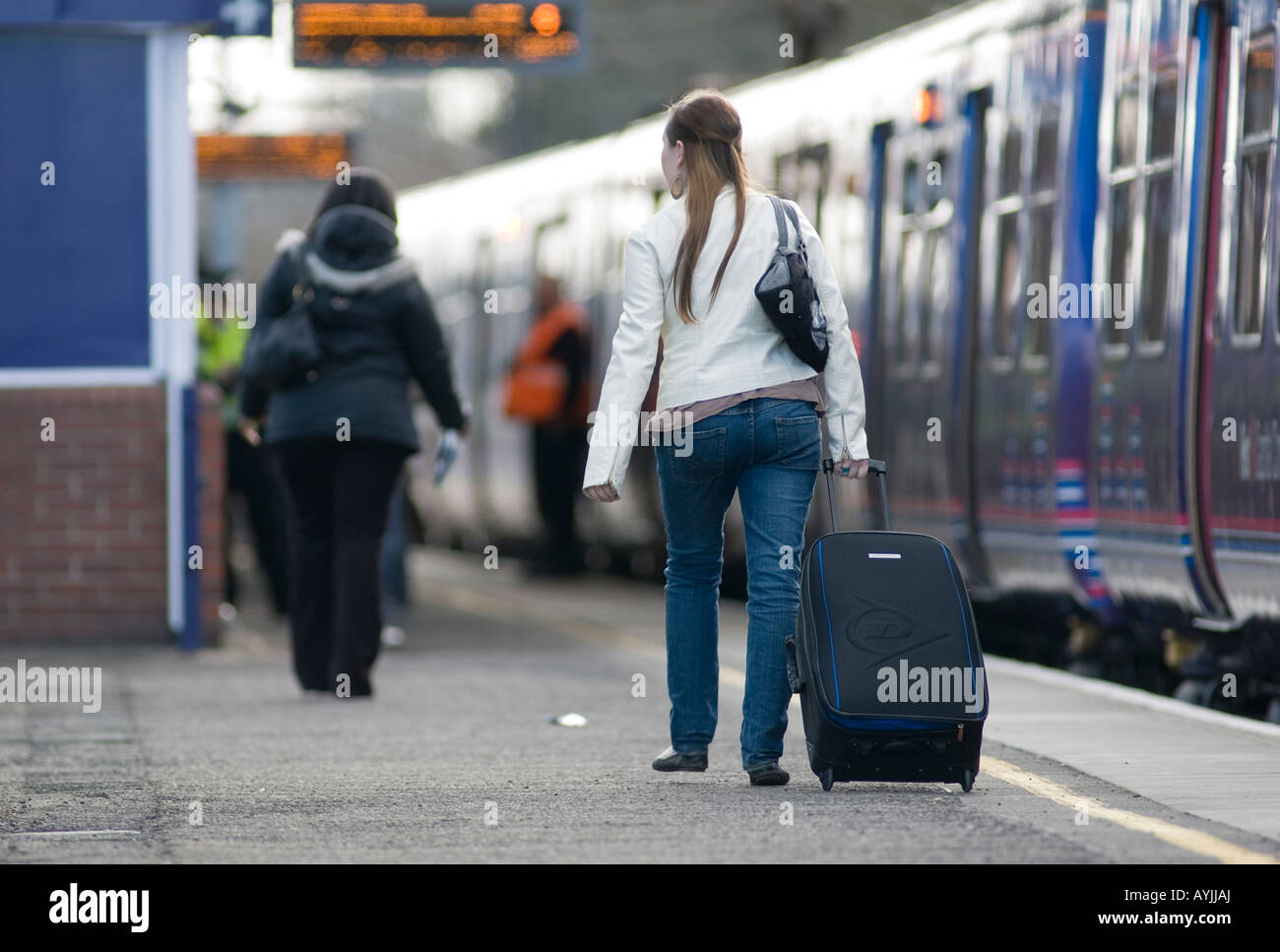 passenger pulling a suitcase along the platform of a uk railway station having just got off of a train Stock Photo