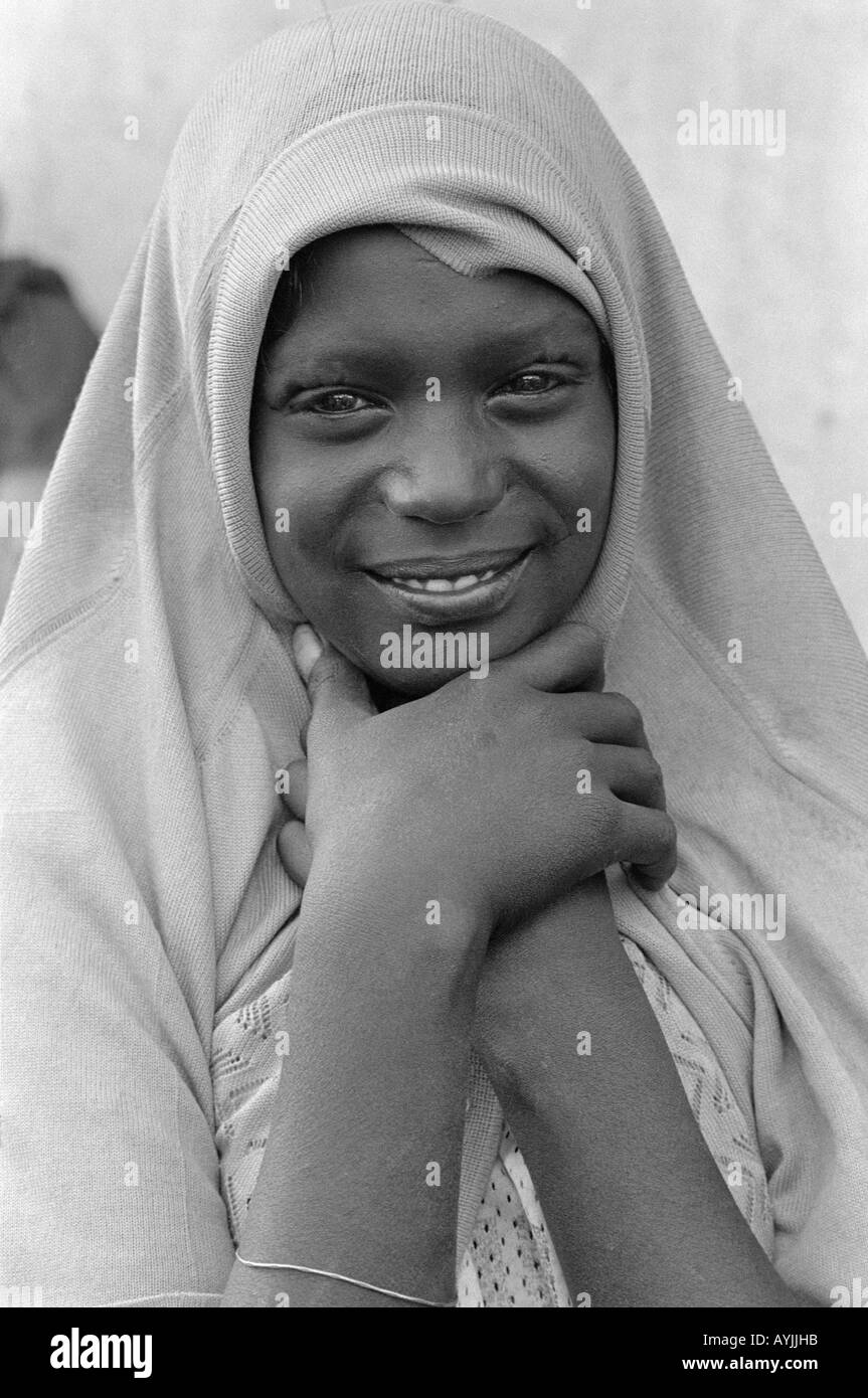 B/W portrait of a smiling beautiful young Muslim girl covering her head with her sweater. Harar, Ethiopia, Africa Stock Photo