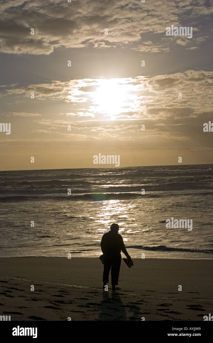 Silhouette of man watching evening sun setting over sea and beach Praia de Mira Portugal Stock Photo