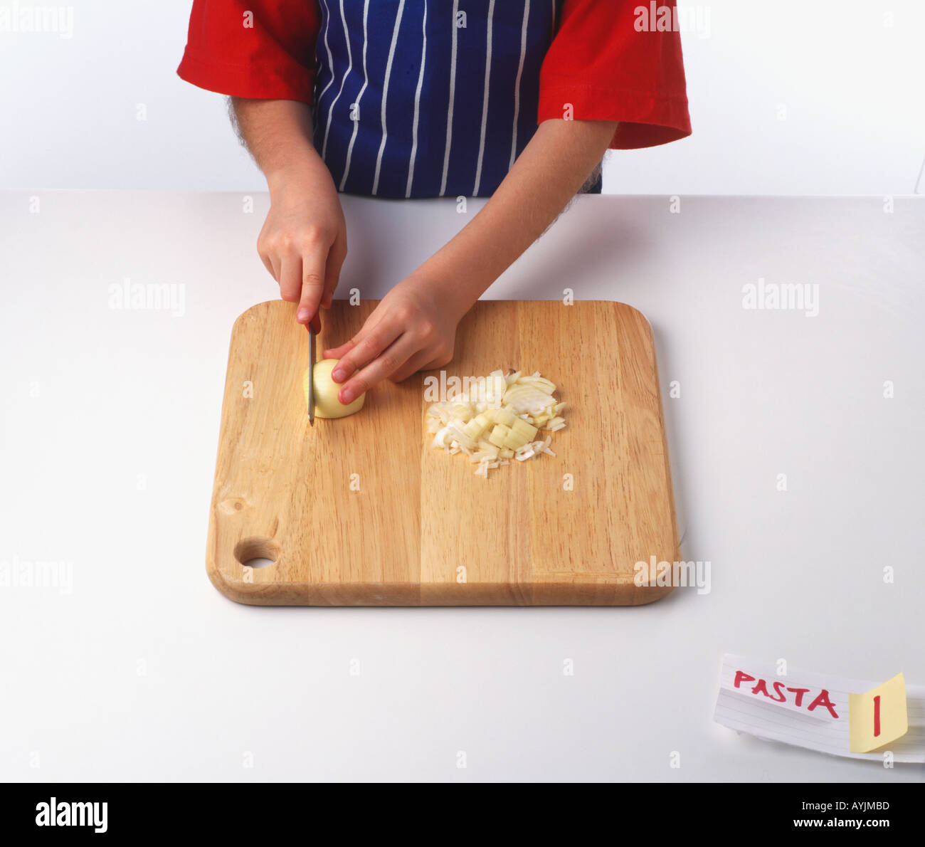 Chopping onion finely on a wooden choppingboard Stock Photo