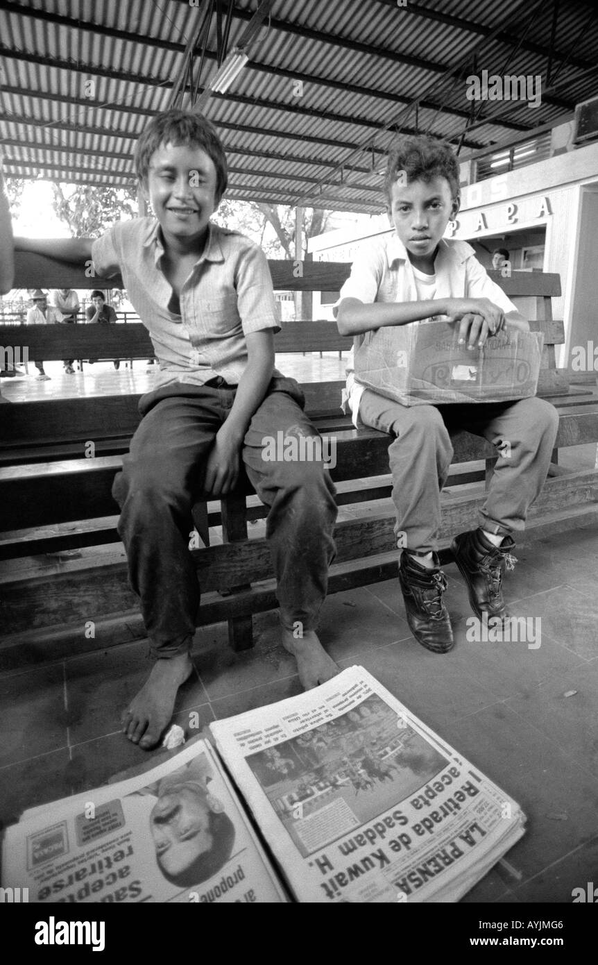 b/w of two street boys selling newspapers and cigarettes at a bus station in San Pedro Sula. Honduras Stock Photo