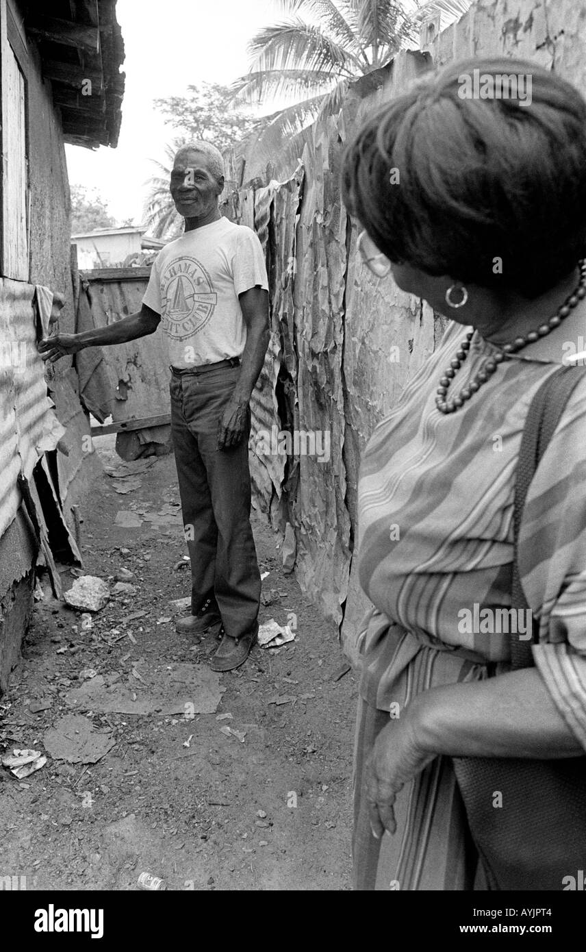 B/W of a female visitor from social services and a destitute elderly man living in the poorest part of Spanish Town. Jamaica Stock Photo