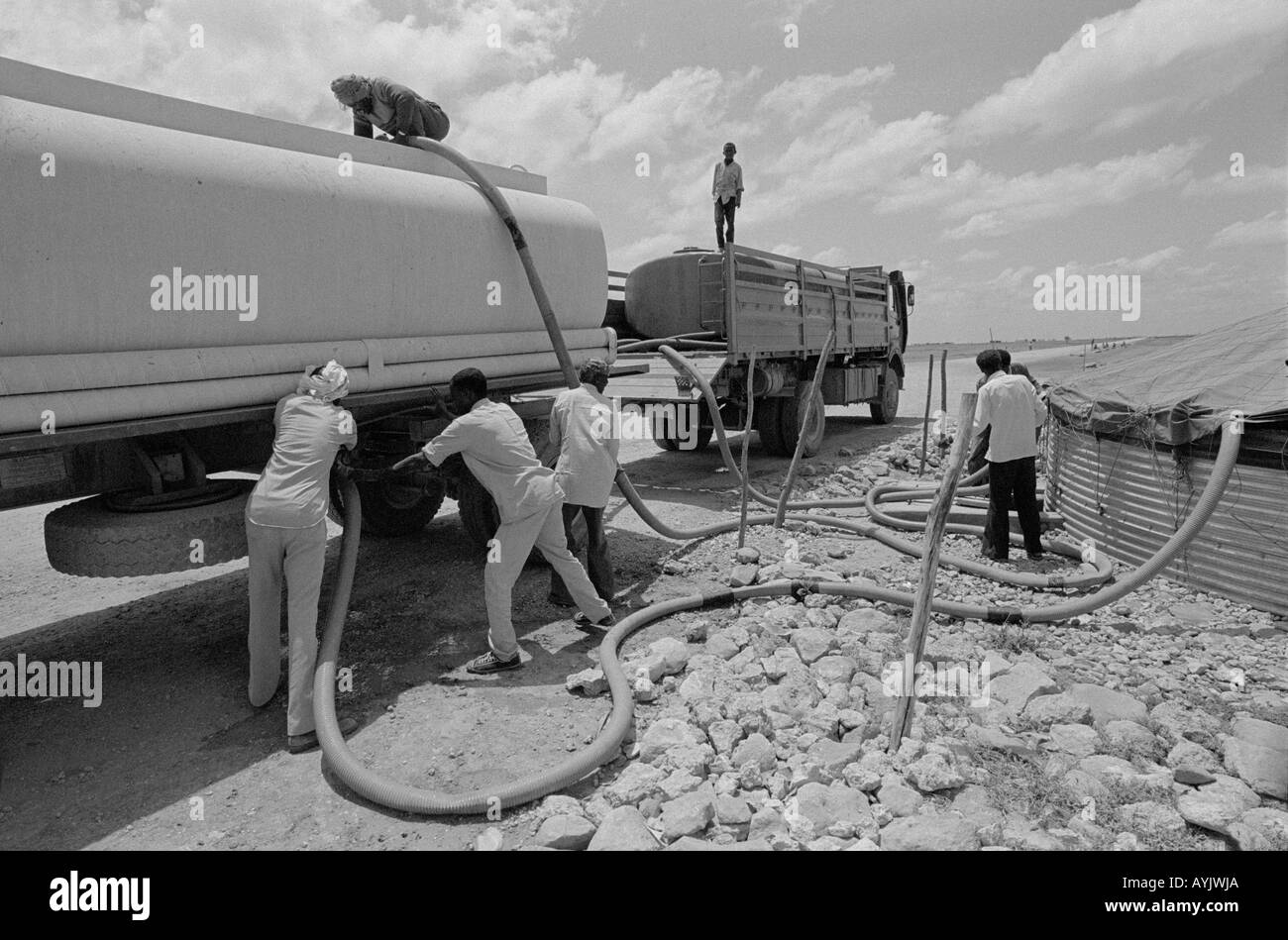 B/W of men at a water tanker filling a storage tank at a refugee camp for displaced Somalis. Kebrebeyah, Ethiopia, Africa Stock Photo