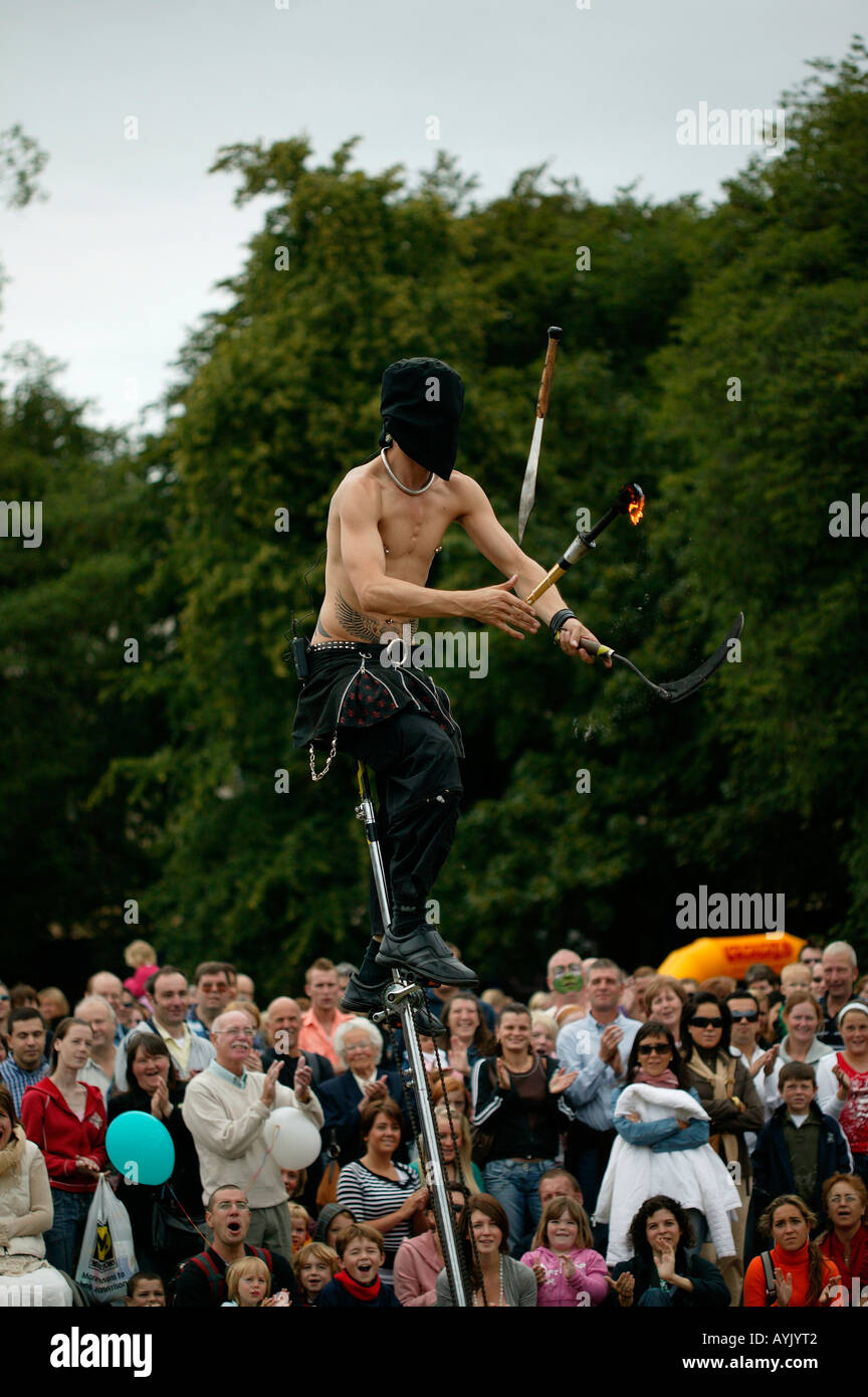 Male Street Performer wearing black hood juggling knife and fire torch, Edinburgh Fringe Sunday, Scotland Stock Photo