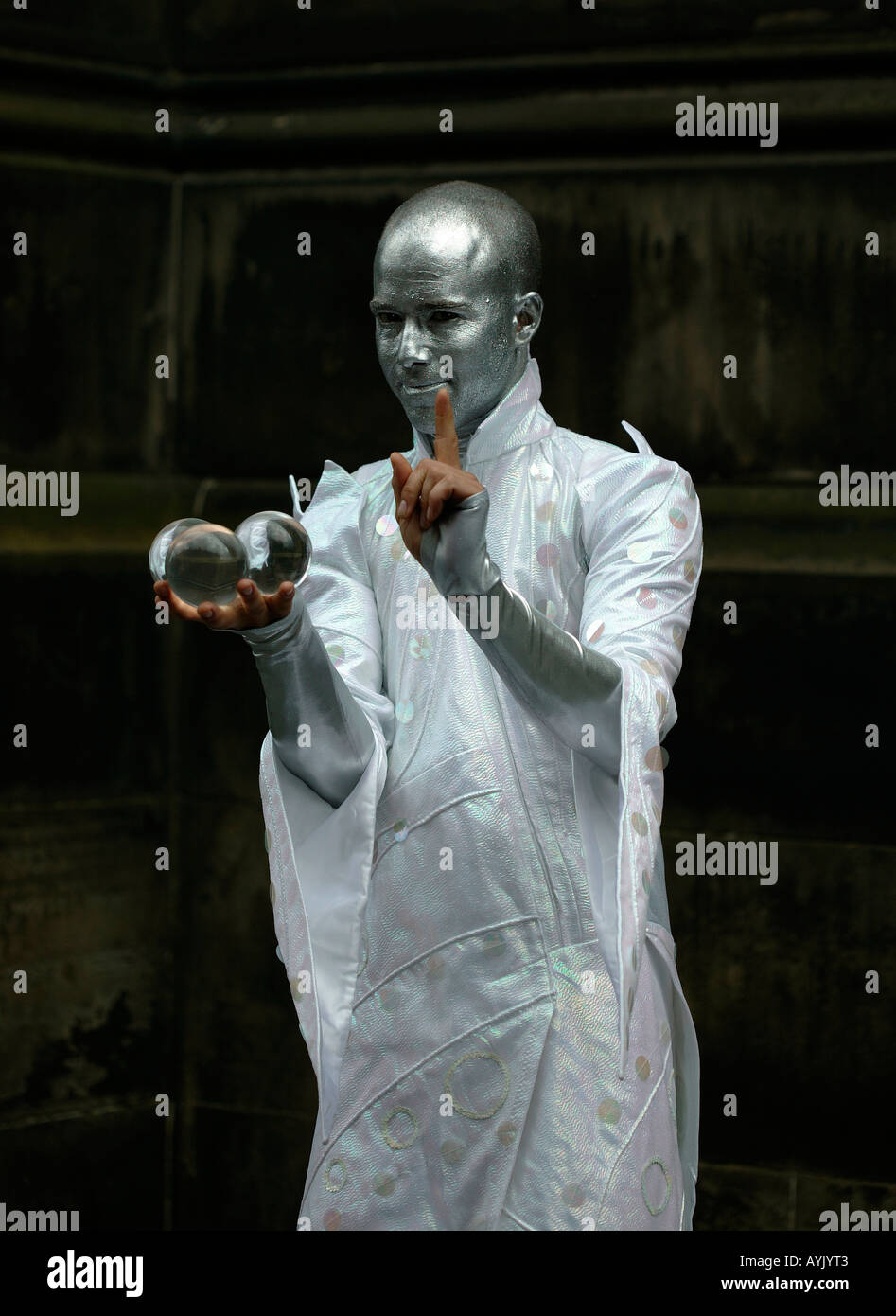 Male Street Performer dressed in silver entertaining with crystal balls Edinburgh Fringe Festival, Scotland Stock Photo