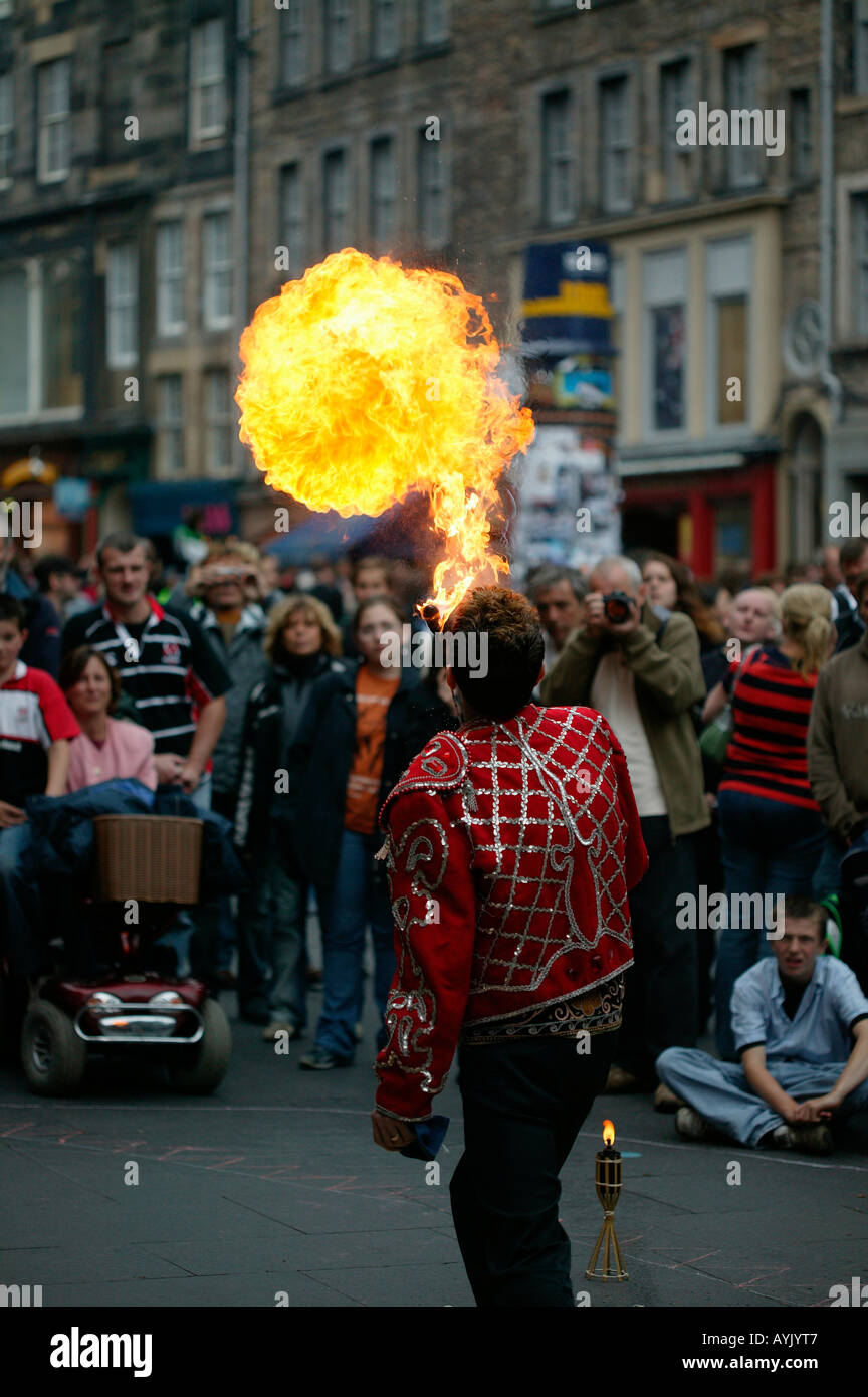 Street Performer blowing ball of fire with audience looking on Edinburgh Fringe Festival, Scotland Stock Photo