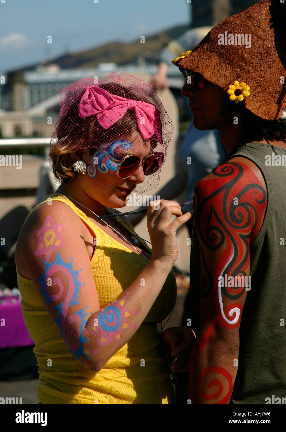 Colourful body painter completing work on a male subject, Edinburgh Fringe Festival, Scotland Stock Photo