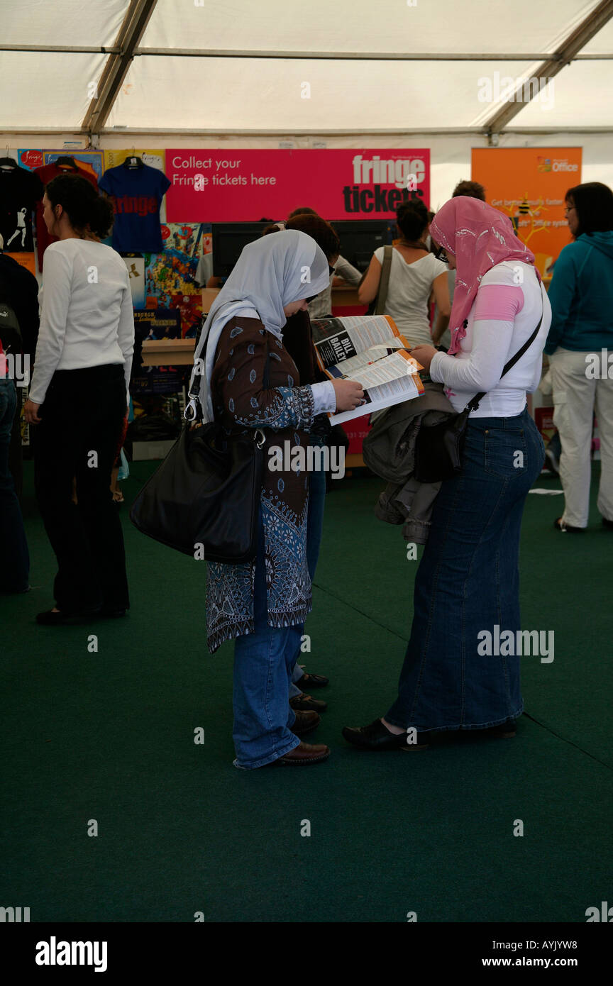 Muslim women wearing scarves looking at Edinburgh Fringe Festival Brochures Scotland Stock Photo