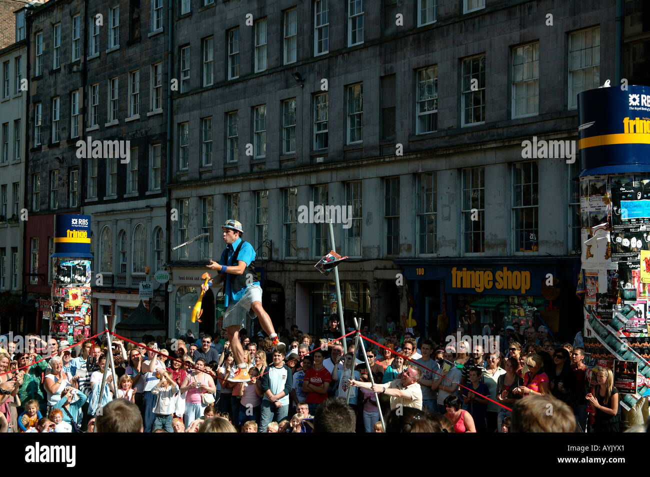 Male Street Performer juggling instruments while balancing on tight rope, Edinburgh Fringe Festival Scotland Stock Photo