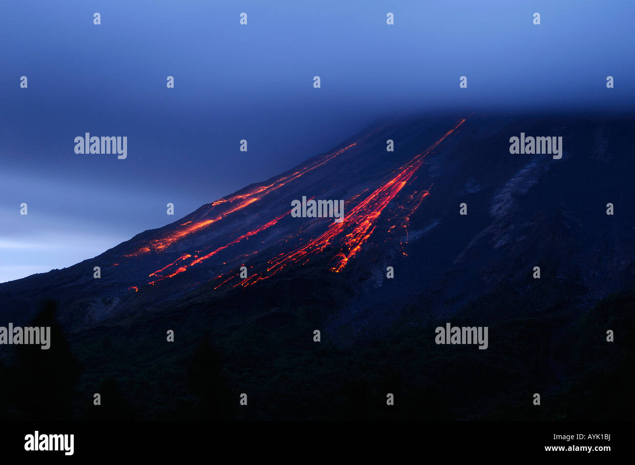 Molten cinder blocks falling down Arenal volcano in Costa Rica at dusk Stock Photo