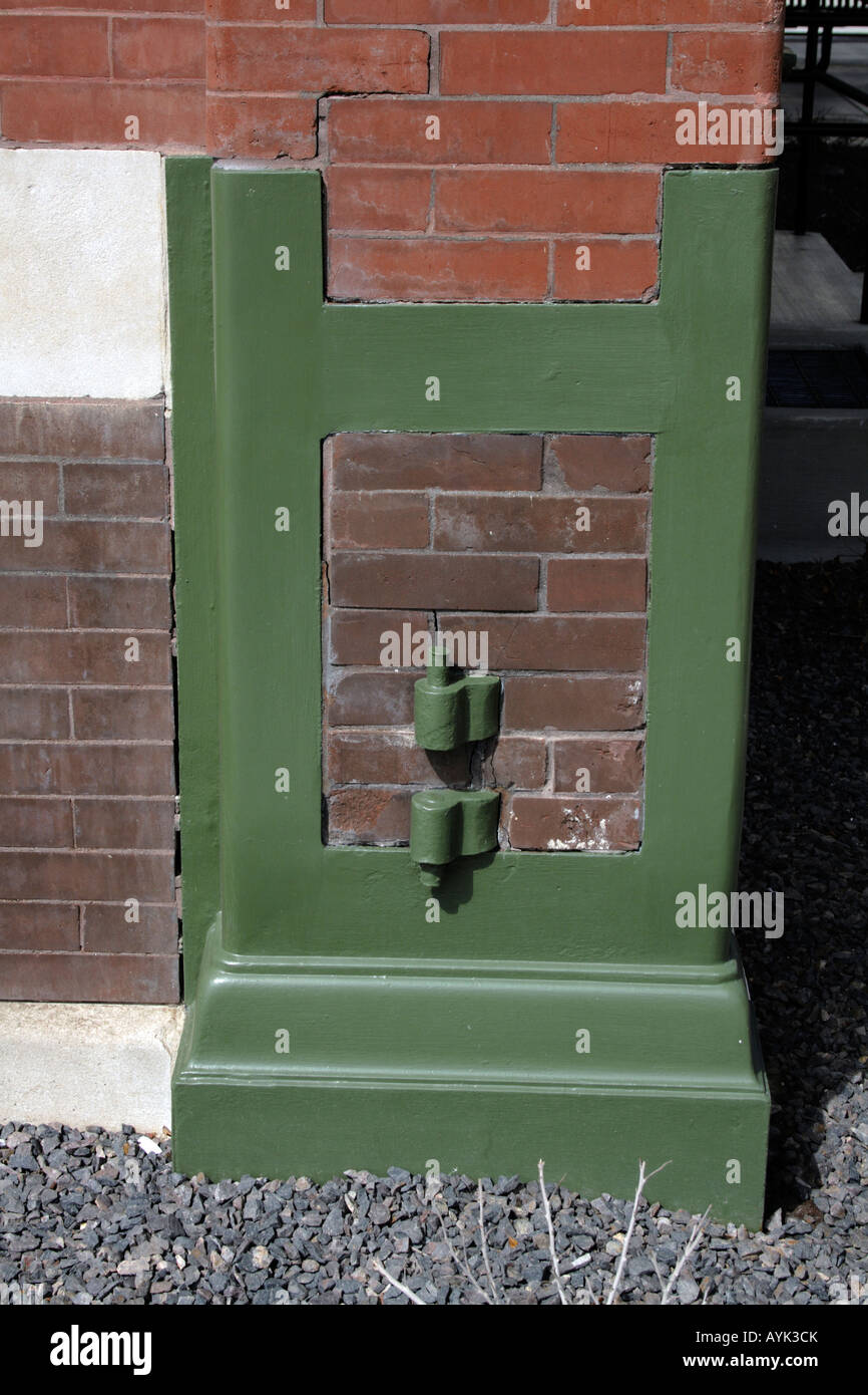 Hinge pivots and protective iron corner, painted green, embedded in brick. Stock Photo