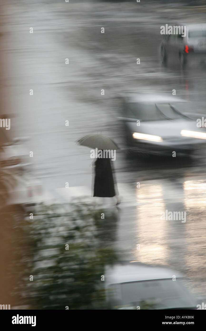 woman crossing road with umbrella in rain Stock Photo - Alamy