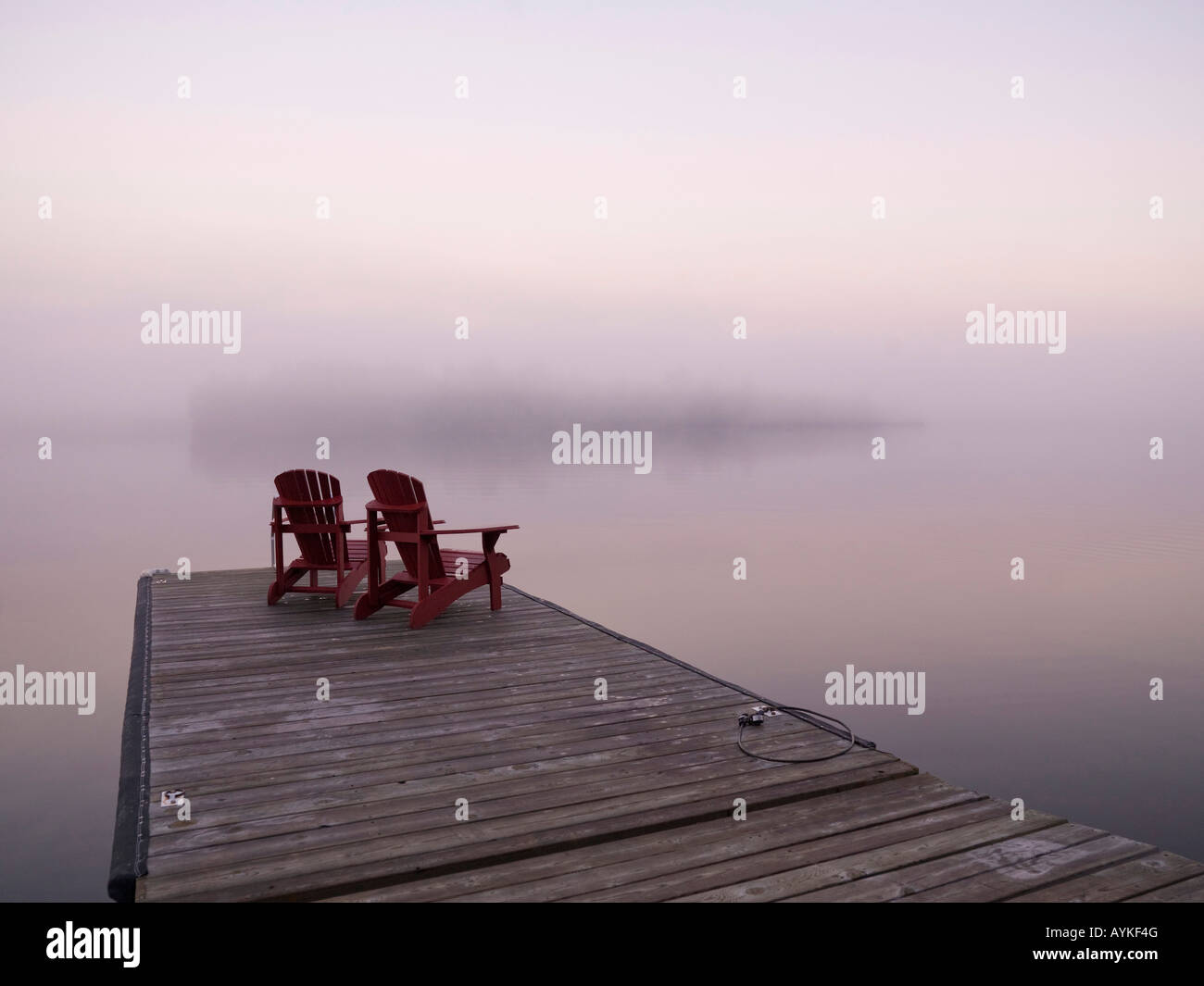 Lake of the Woods, Ontario, Canada, Two red Adirondack chairs on a dock ...