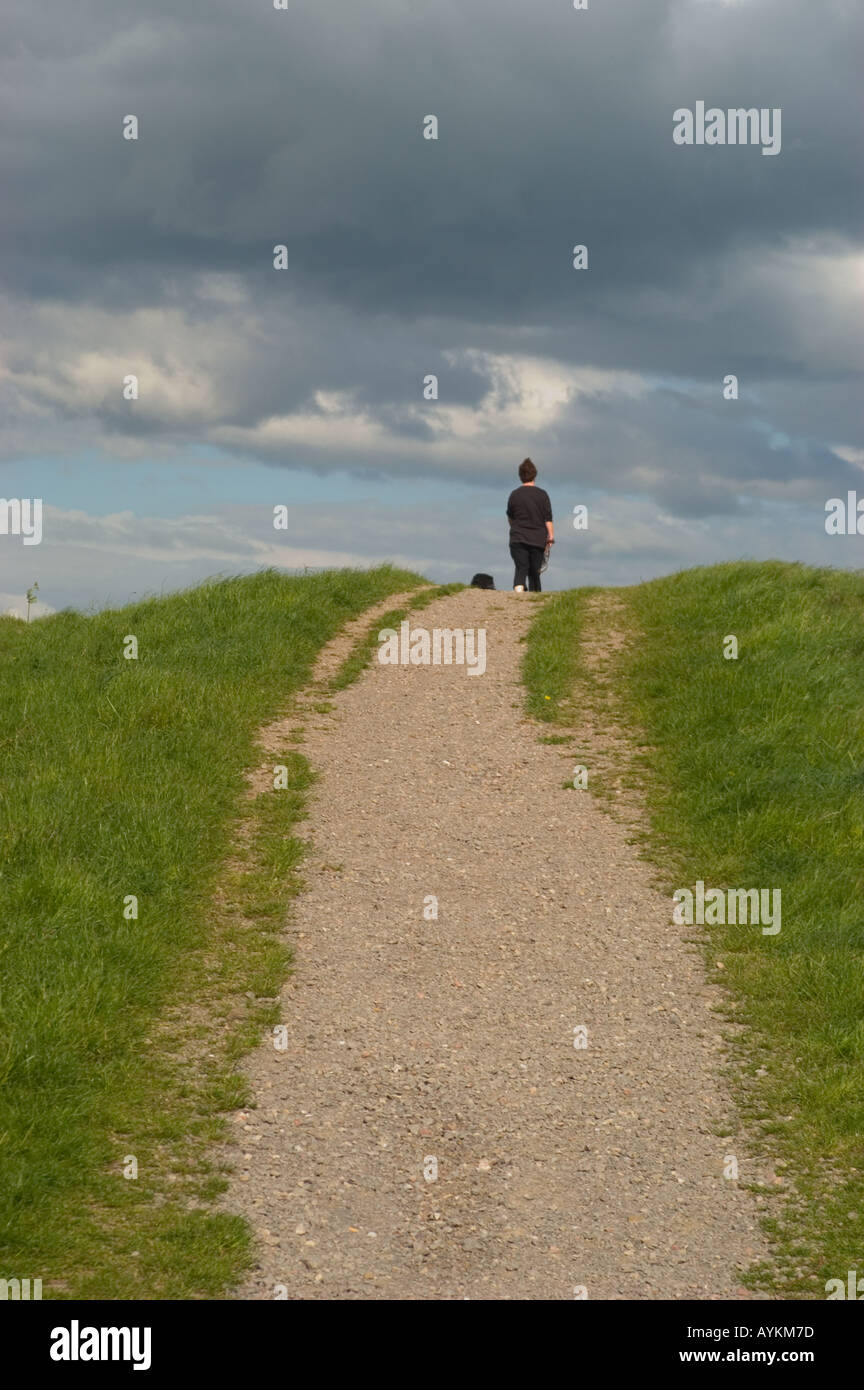 Dog Walker reaches the top of a hill Stock Photo
