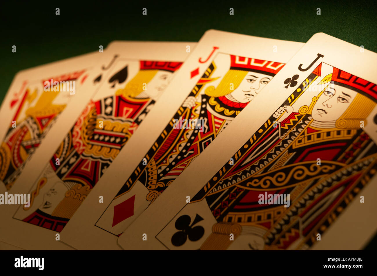 HAND OF PLAYING CARDS DISPLAYING FOUR JACKS ON GREEN CLOTH GAMING TABLE Stock Photo