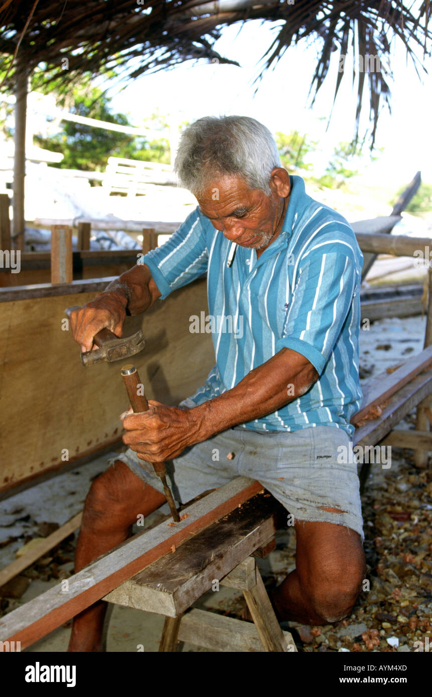 Philippines Palawan Dumaran Island crafts boat builder cutting joint in wood with chisel Stock Photo