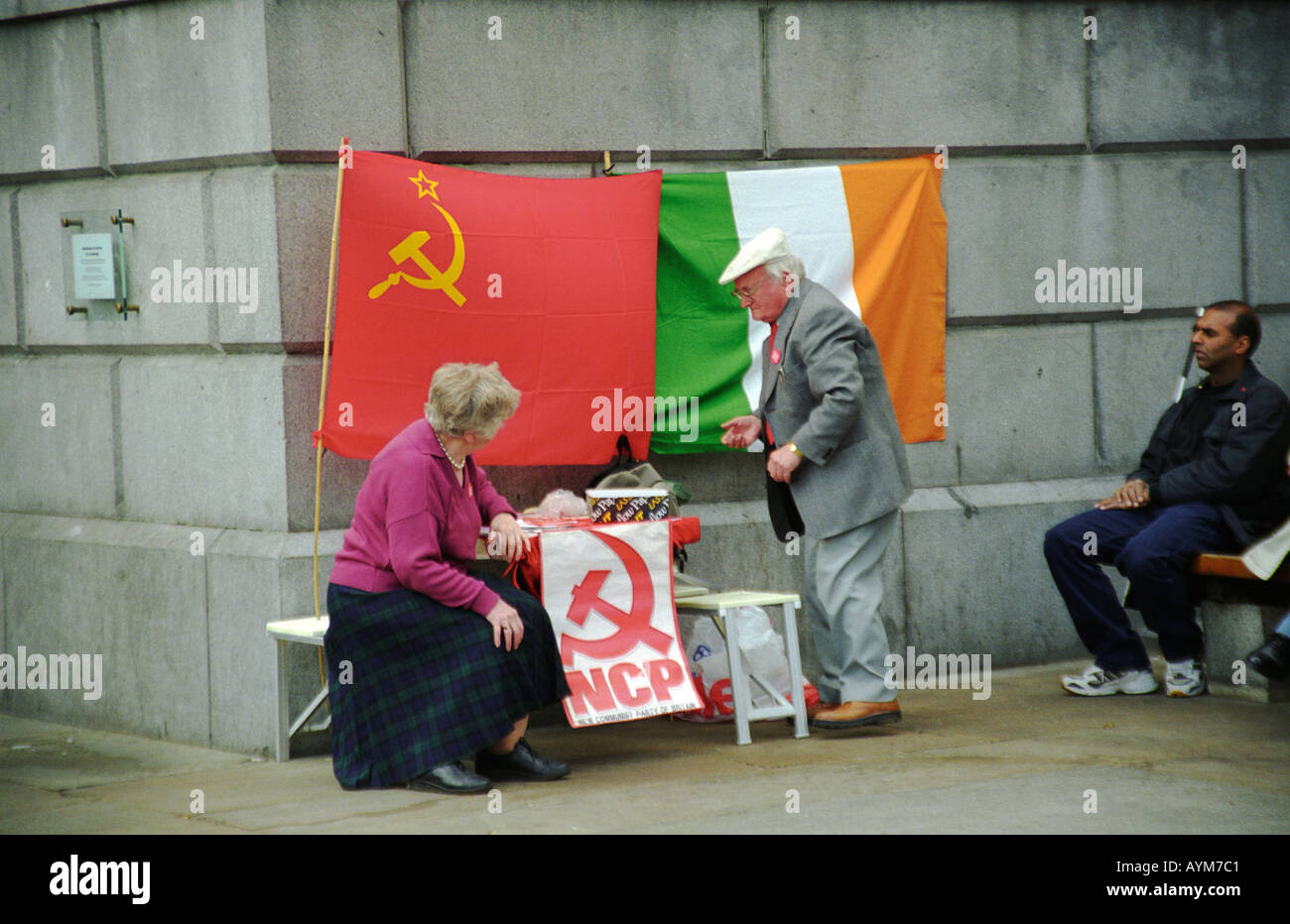 An elderly couple displaying the New Communist Party flag at the Anti capitalist protest on May Day 2000 in London Stock Photo