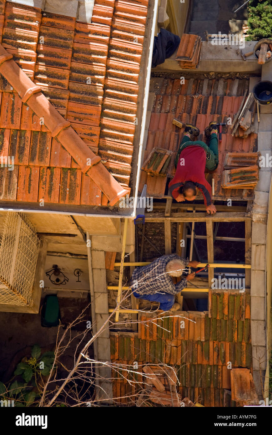 Two roofers repairing a tiled roof in southern France. Stock Photo