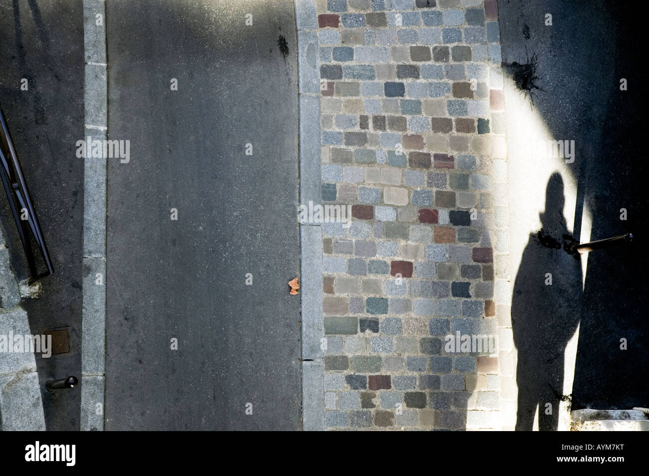 Shadow of a man on a cobblestone street with sinister overtones. Stock Photo