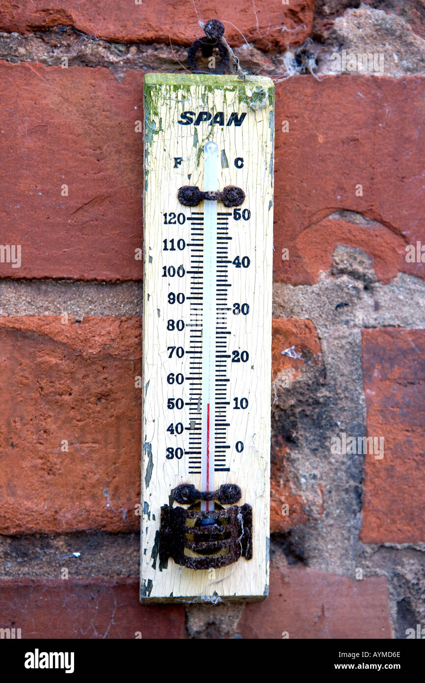 Old Span thermometer showing 50 degrees Fahrenheit against a distressed red brick wall Stock Photo