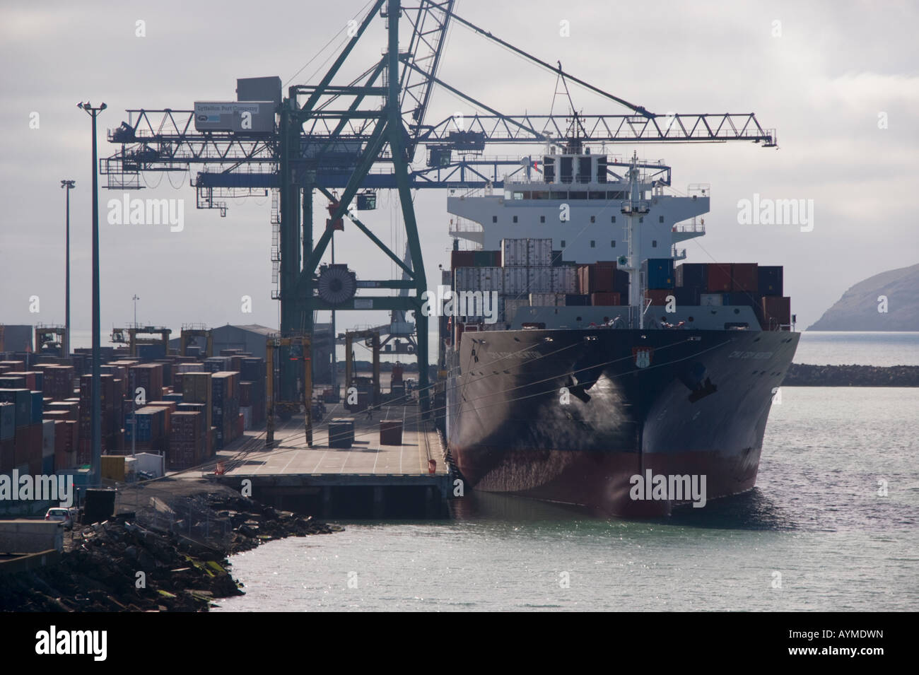 A container ship alongside the dock with shore cranes at work, Lyttelton, New Zealand Stock Photo