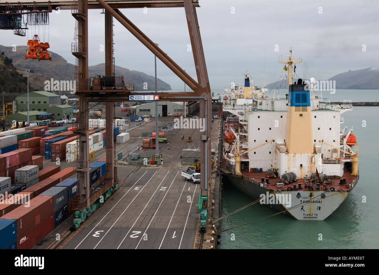 2 bulk carrying cargo ship moored alongside the quay at Lyttelton, New Zealand. The legs of a container crane dwarf the ships. Stock Photo
