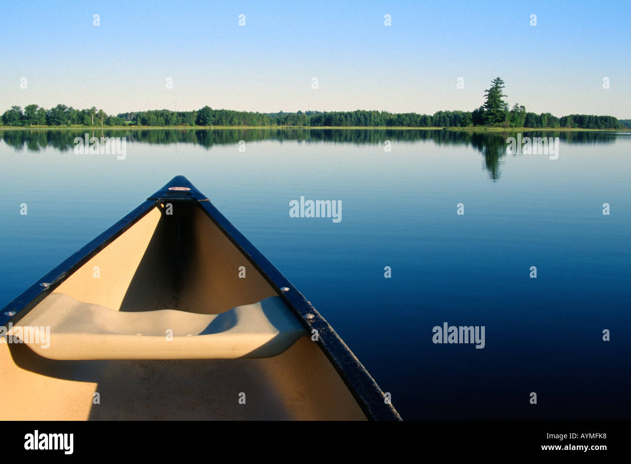 Paddling a canoe across a still lake in Northern Minnesota Stock Photo