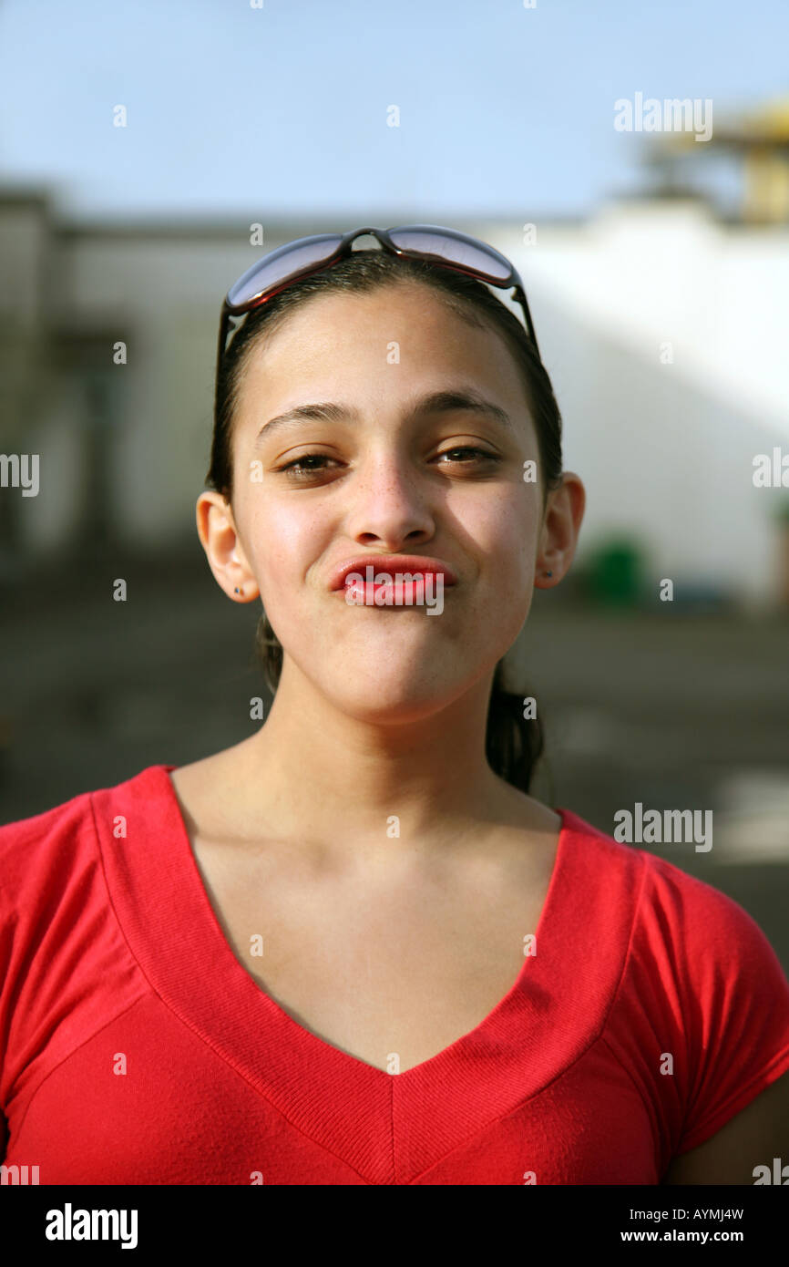 A teenage girl in a red top and red lipstick puckers her lips at the camera Stock Photo