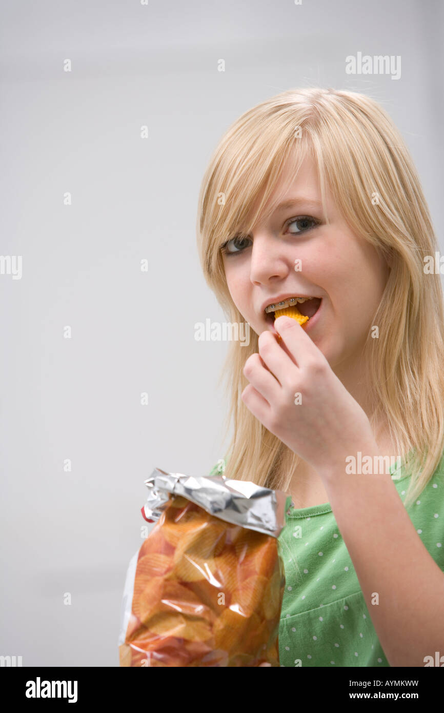 Teenage girl with braces eating chips Stock Photo Alamy