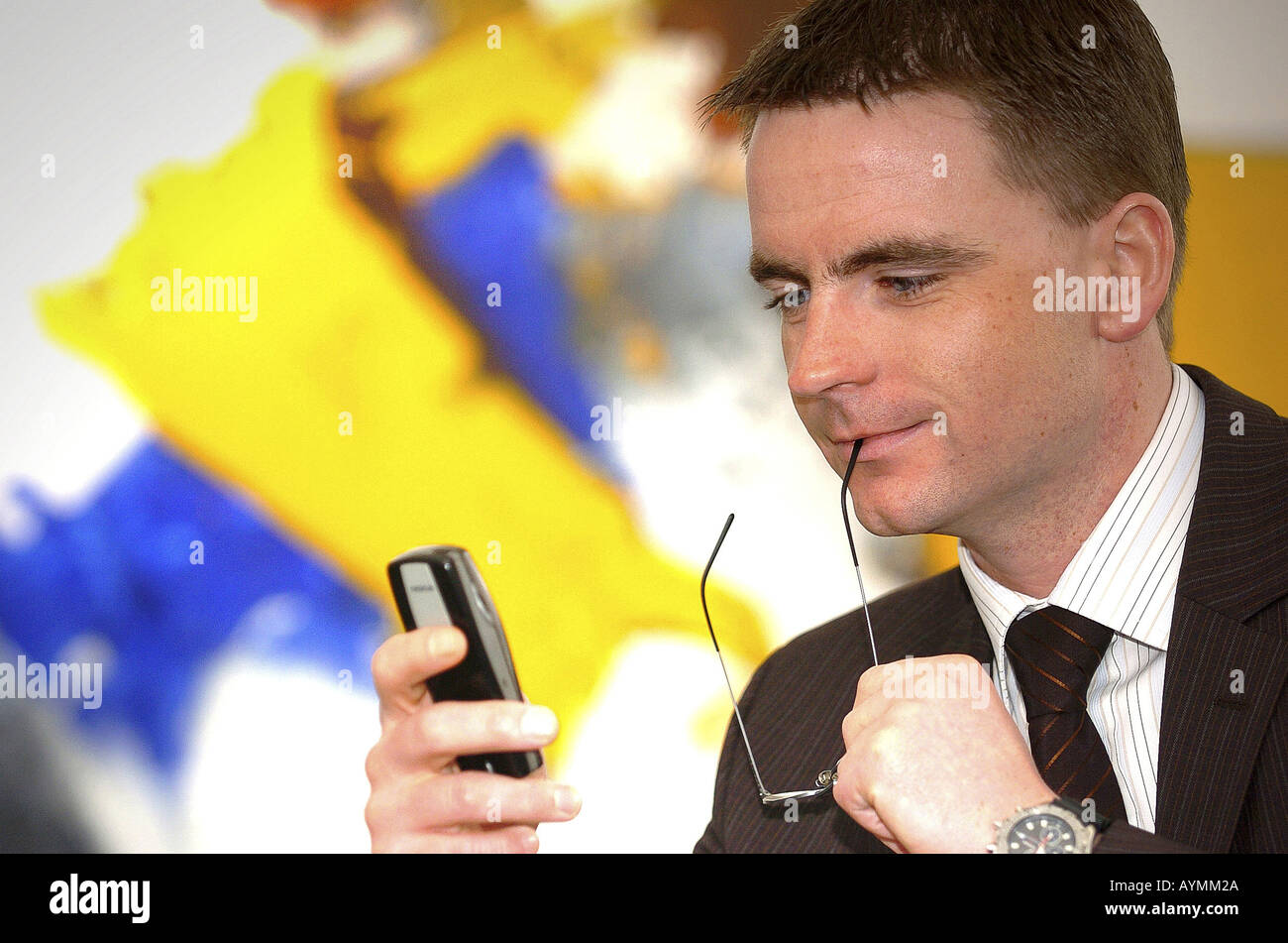 Geschaeftsmann hat zum Bedienen des Mobiltelefons seine Brille abgenommen Stock Photo