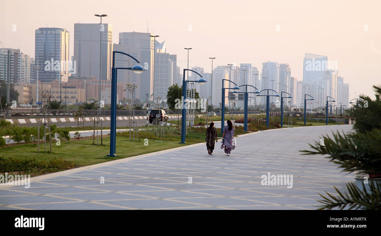 Two arab women walk along the Corniche at dusk, Abu Dhabi city, Abu Dhabi, UAE Stock Photo