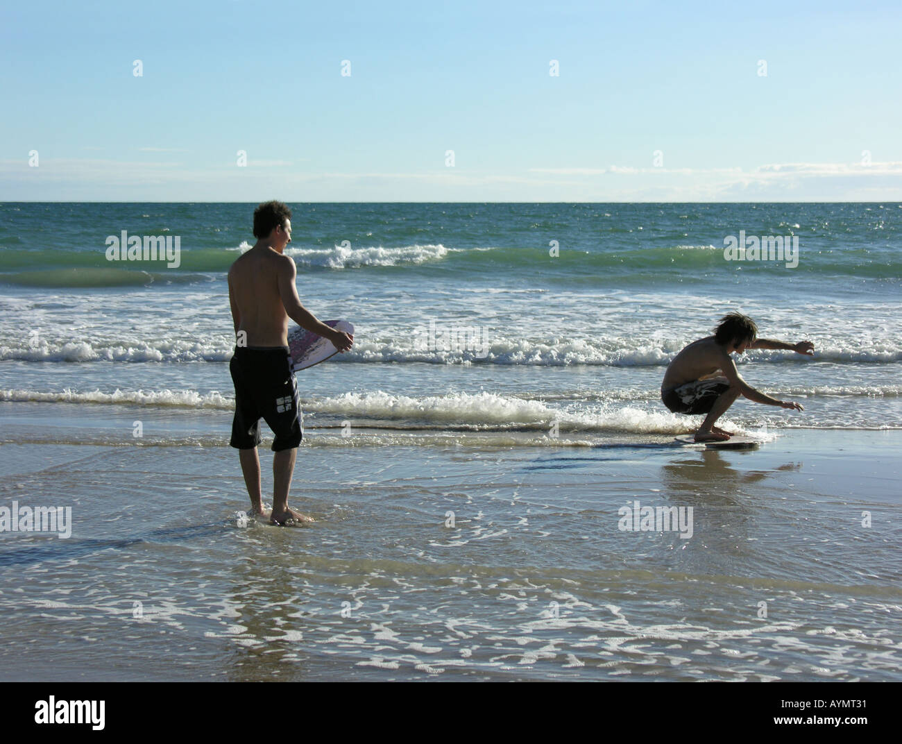 Teen boys with skimboards on the beach Stock Photo