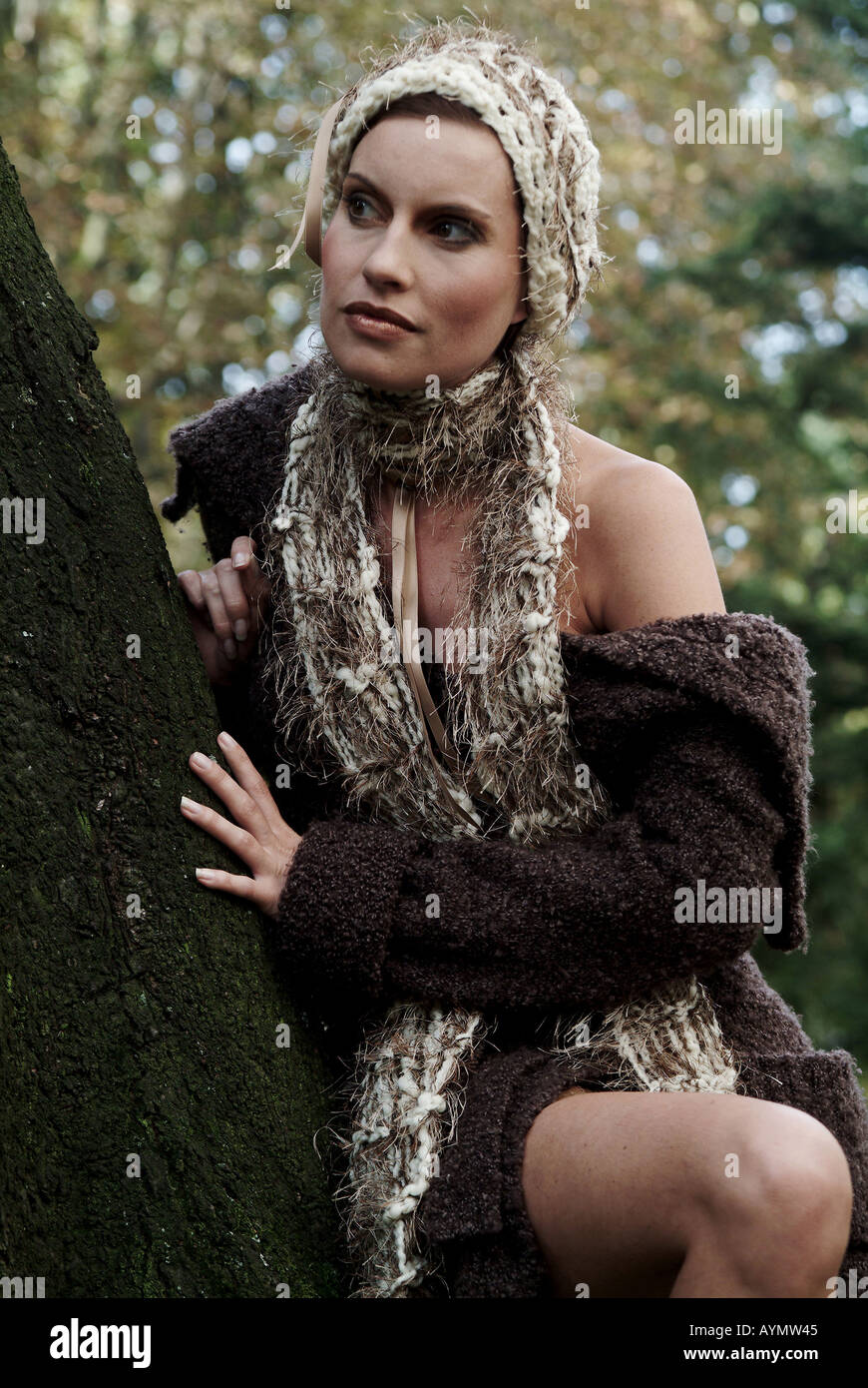 Frau in Wollkleidung lehnt an einem Baum Stock Photo