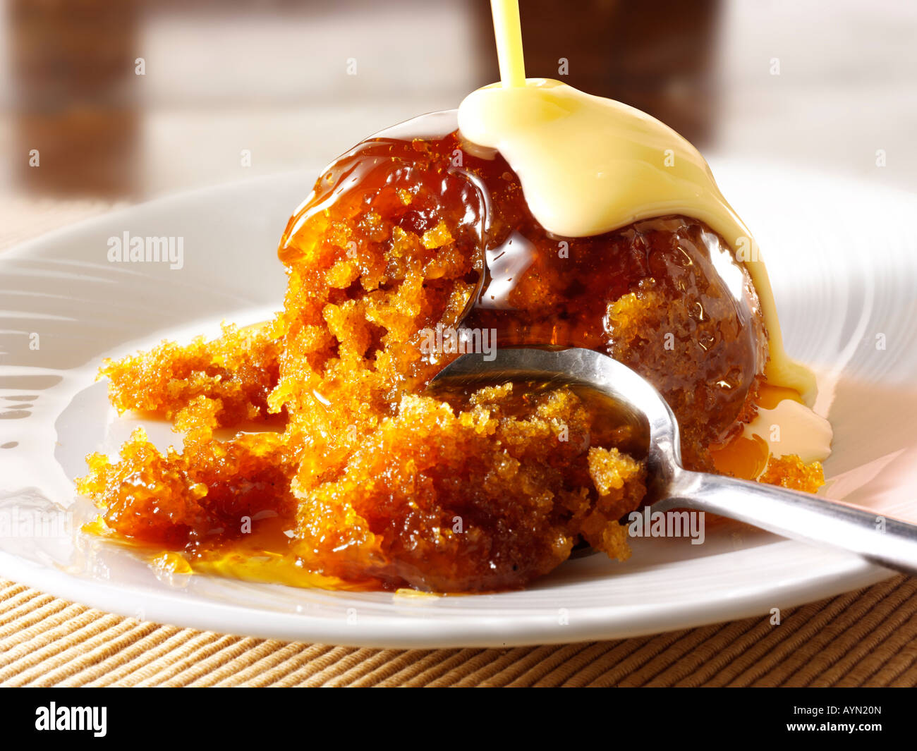 Traditional British Sticky Toffee sponge Pudding and custard dessert being served onto a plate Stock Photo