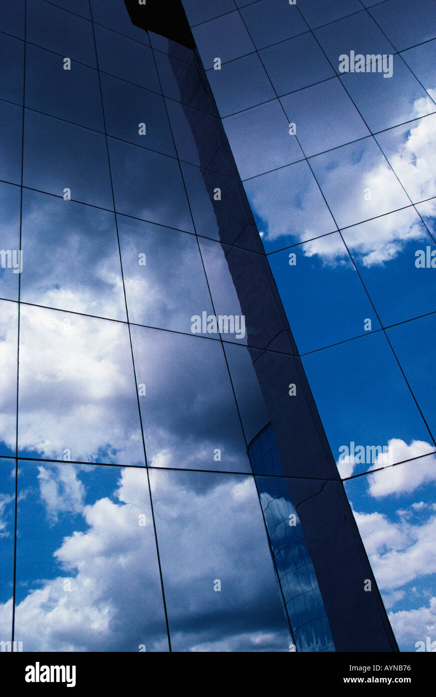 Contemporary glass and steel office tower reflecting clouds and blue ...