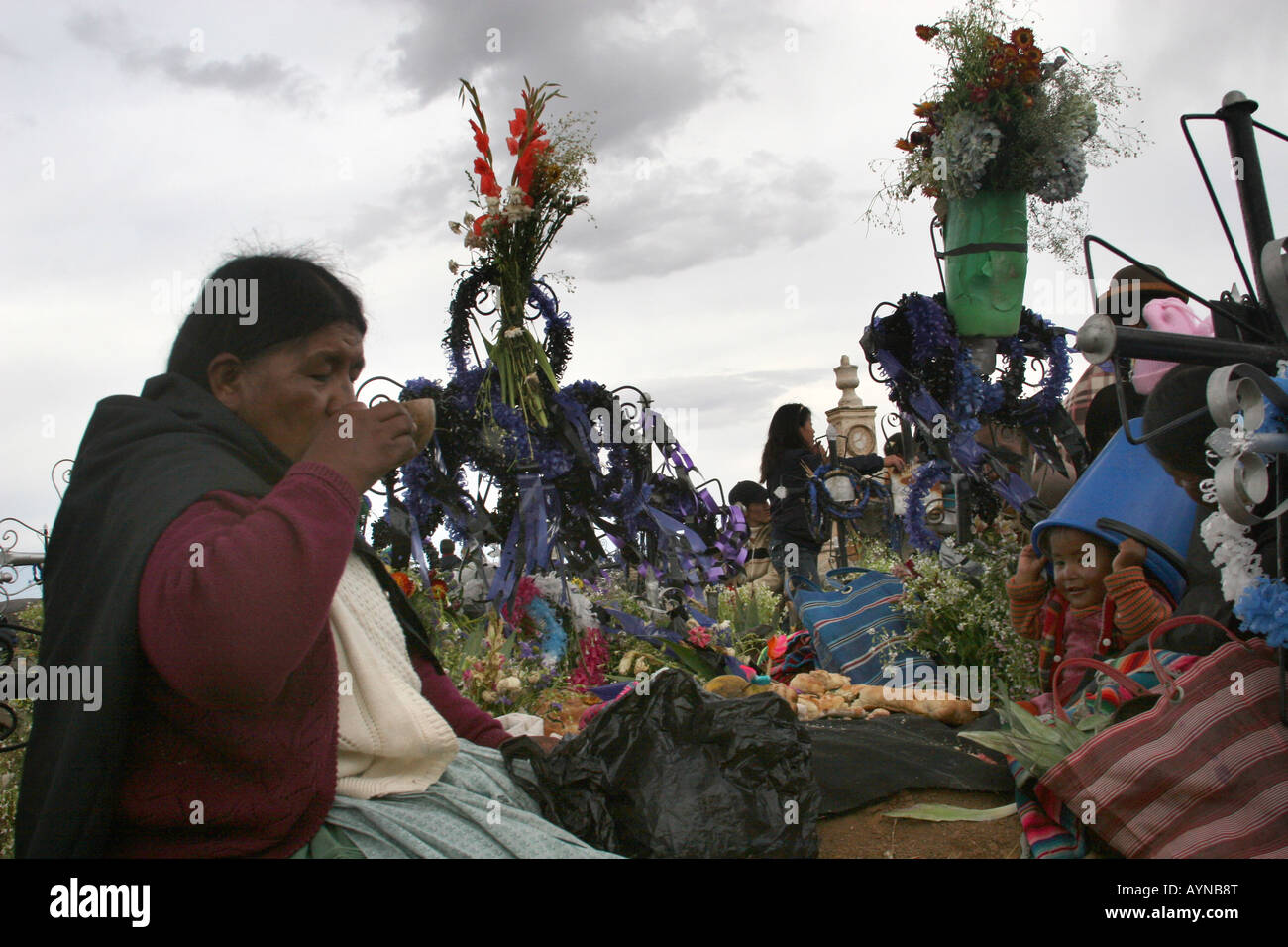 A traditional Bolivian woman drinking chicha in front of her husband's grave iat the cemetery in llallagua, Bolivia Stock Photo