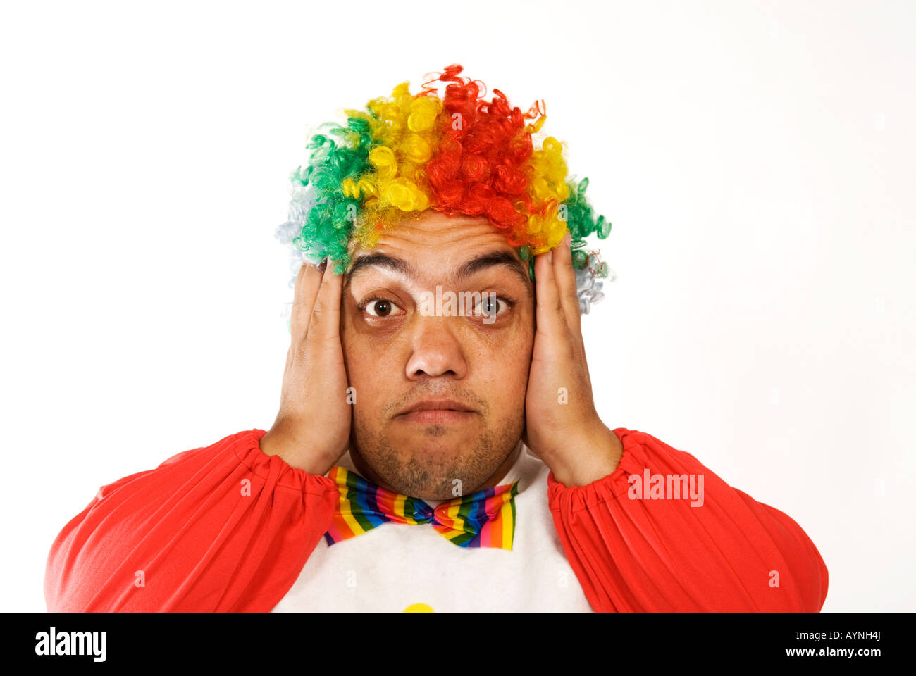 Head and shoulders portrait of a surprised midget clown hands on ears against a white background Stock Photo